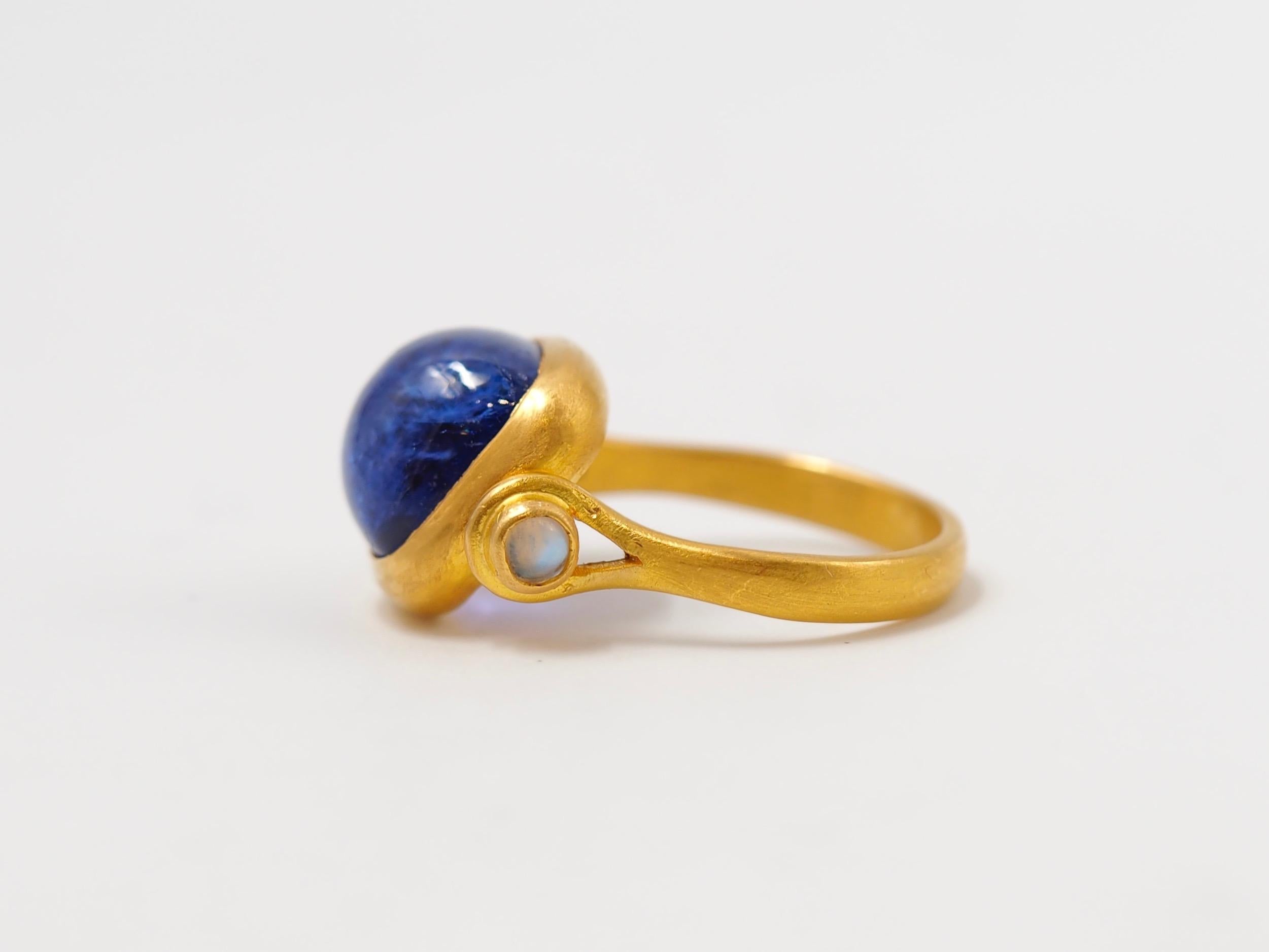 This antique style ring by Scrives is set with a purplish blue tanzanite sugarloaf cabochon of 6.46 cts. and 2 cabochon moonstones of 0.17cts on the side.
The central stone and its setting are slightly turning/moving in order to give more comfort.