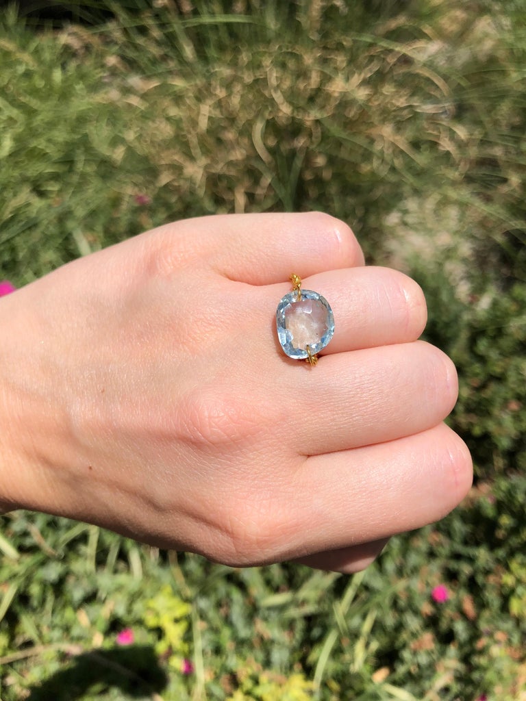 This ring by Scrives is composed of a faceted aquamarine of 6.73cts simply drilled on each side in order to add a handmade 22cts gold chain. 
The aquamarine is natural and shows typical natural inclusions.
The ring can be worn either way, on the