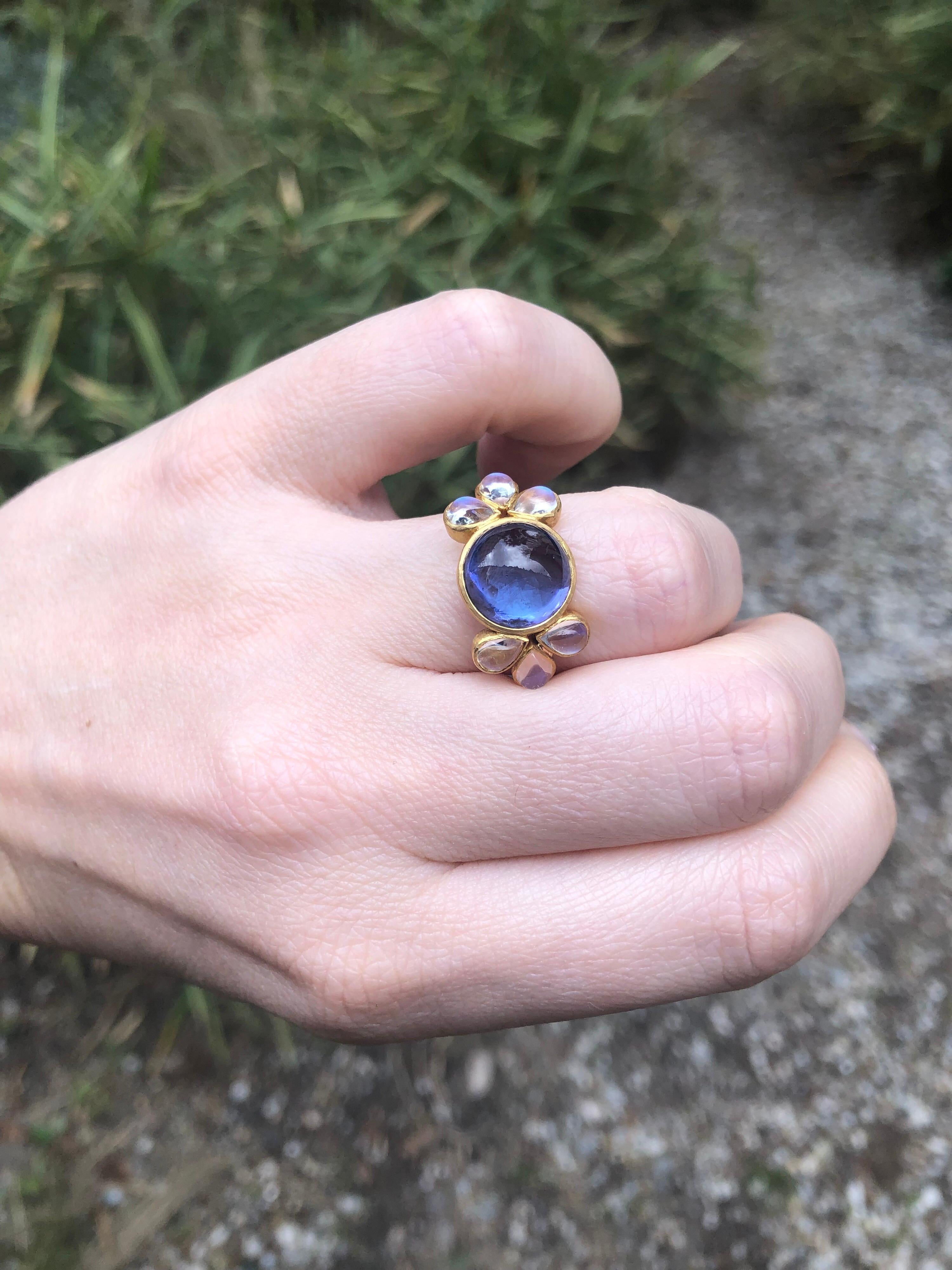 This delicate ring is composed of an intense tanzanite cabochon of 6.95 cts surrounded by 6 moonstones cabochons (total weight: 2.07cts). The tanzanite is natural with typical eye visible inclusions. Its colour is blue with a very slightly purple