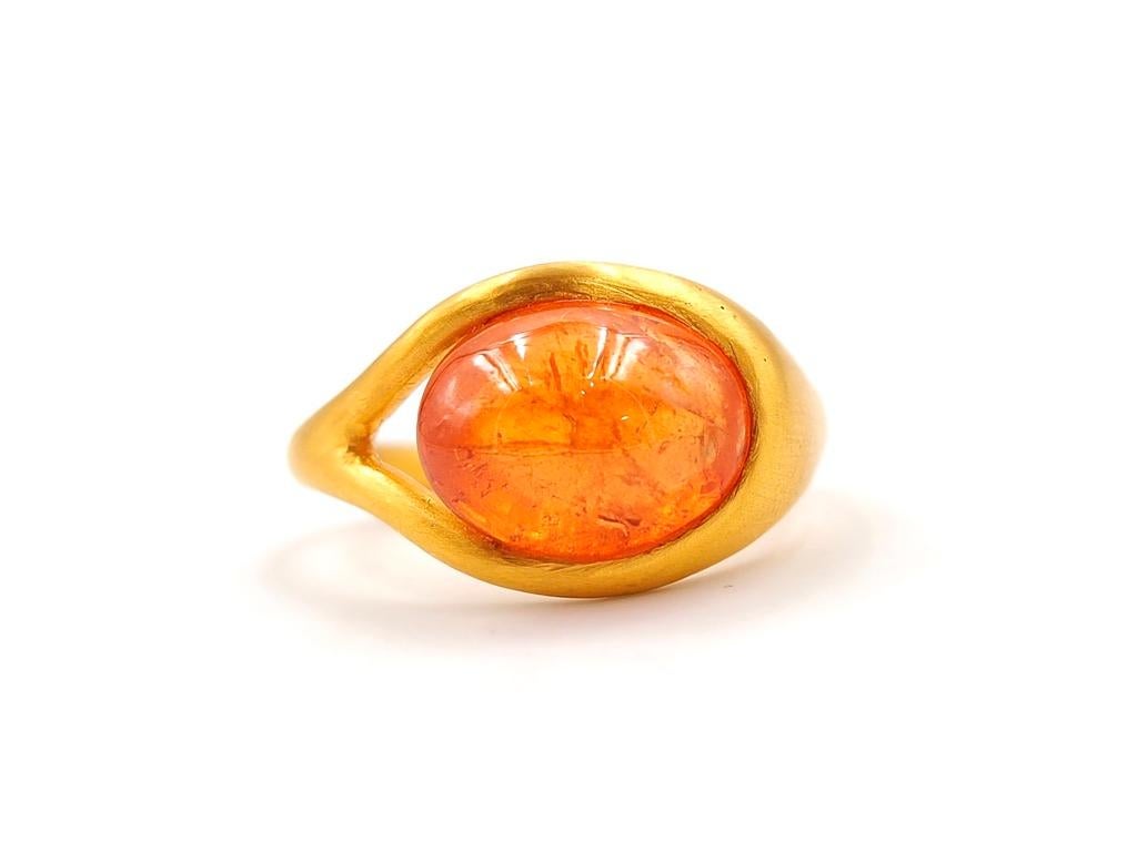 This delicate ring by Scrives is composed of an orange garnet cabochon of 7.18 cts. 

The stone is hold by 2 gold lines on one side that form the band. This design allows light to come into the stone from the side and put into highlight the stone.