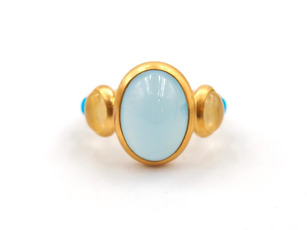 This delicate ring is composed of 5 stones in line: 1 Aquamarine cabochon, 2 natural yellow sapphire cabochons and 2 turquoise cabochons. The center stone is an aquamarine of 7.35 cts and the 2 yellow sapphires have a total weight of 0.93 cts. The 2