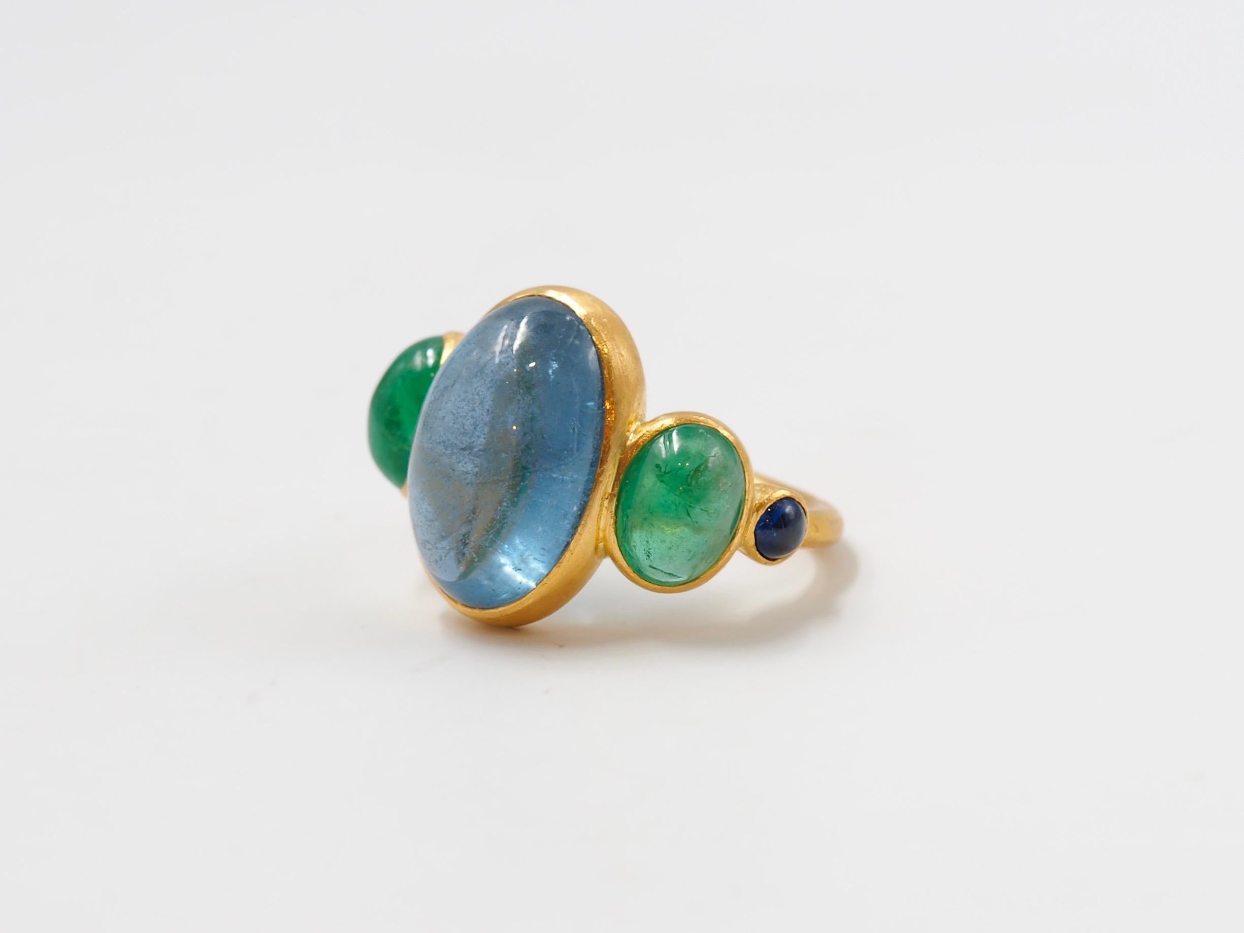This delicate ring is composed of 5 stones in line: 1 deep blue natural aquamarine cabochon, 2 natural emerald cabochons and 2 blue sapphire cabochons. The center stone is an aquamarine of 7.88 cts and the 2 emeralds have a total weight of 2.66 cts.