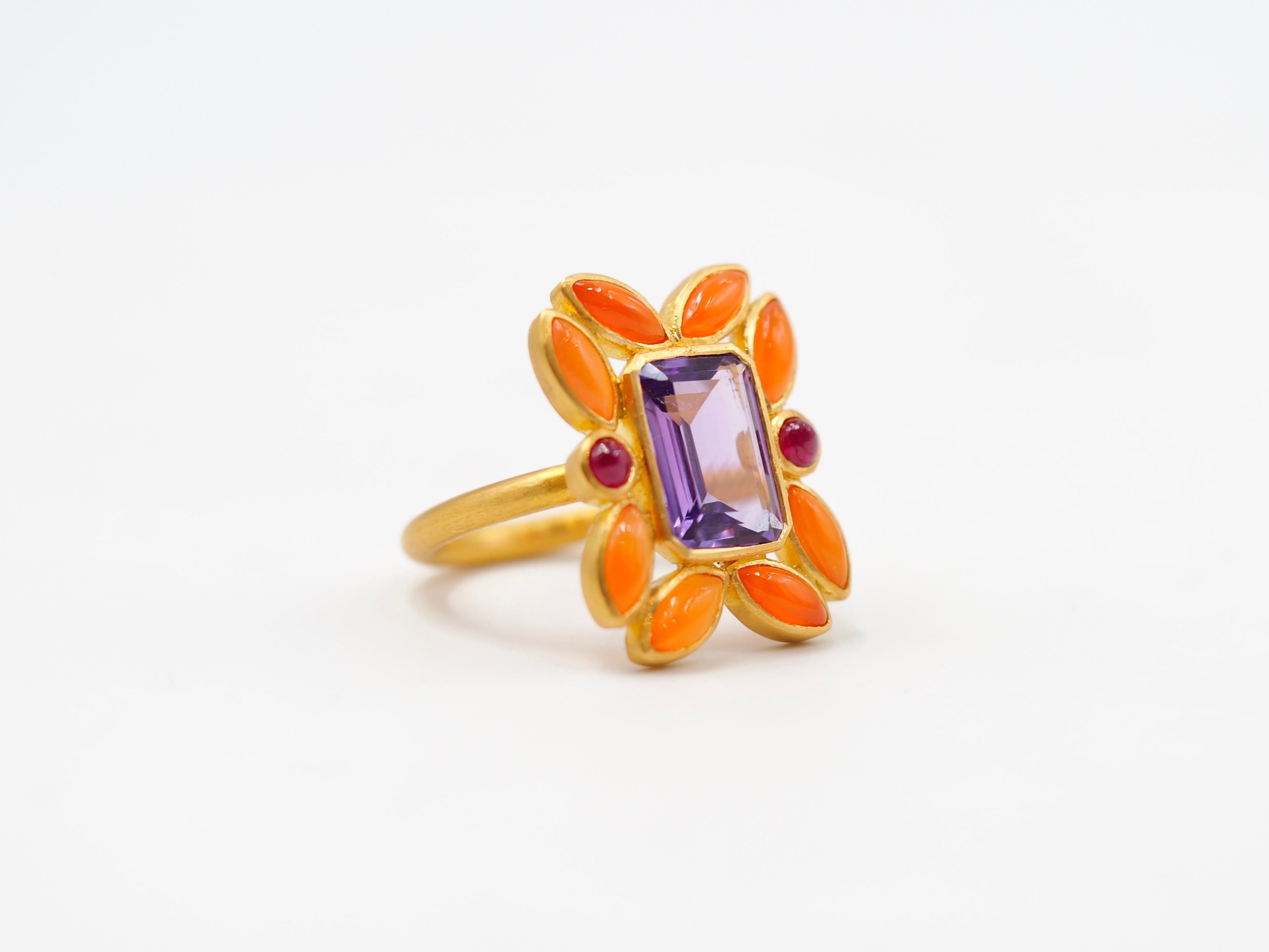 This one-of-a-kind ring by Scrives is composed at its centre of a rectangular natural Amethyst. It is surrounded by 8 marquise shapes Cornalines (orange chalcedony) and 2 Rubies to harmonise the ring design and give a contrasted effect. 
This