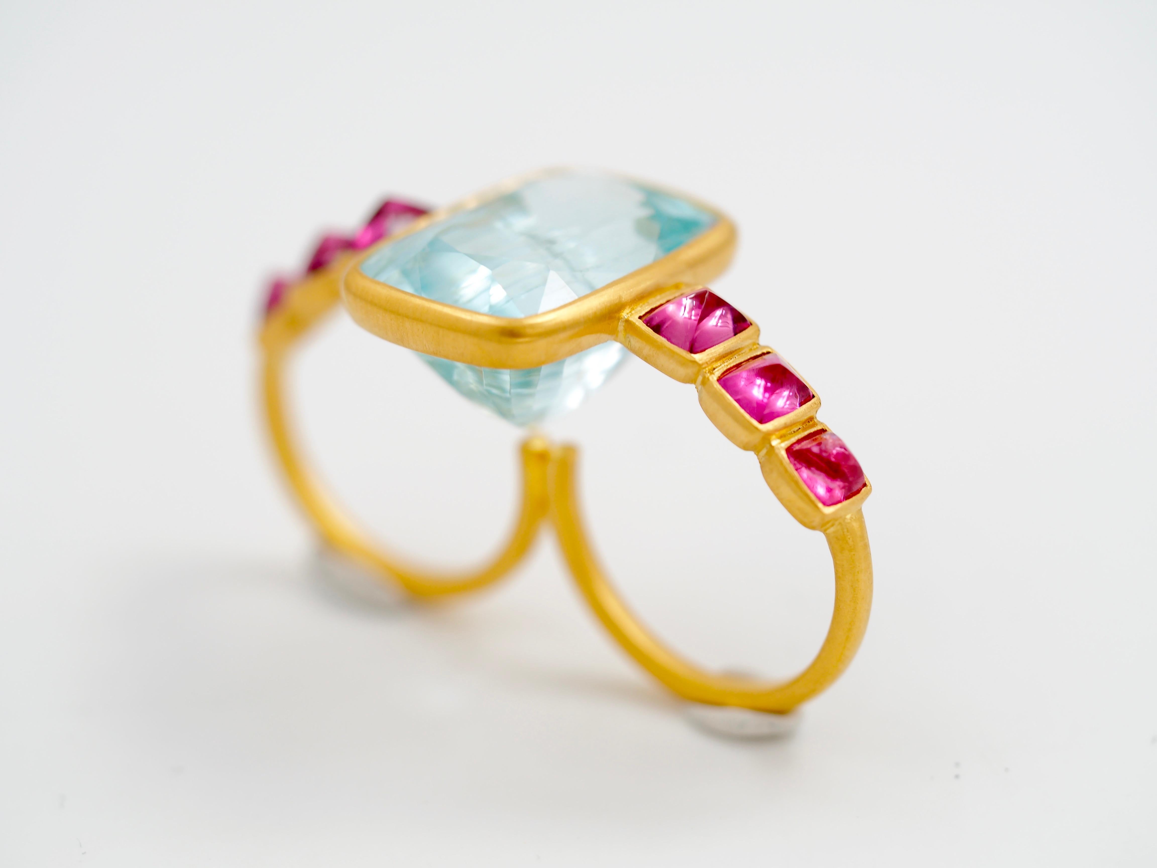 This two-fingers ring by Scrives is composed of a large and deep aquamarine of 19.8cts (origin: Myanmar, no treatment) and of 6 sugarloaf pink spinels set on the sides (total weight: 3.65cts, origin: Myanmar). The aquamarine exhibits eye visible