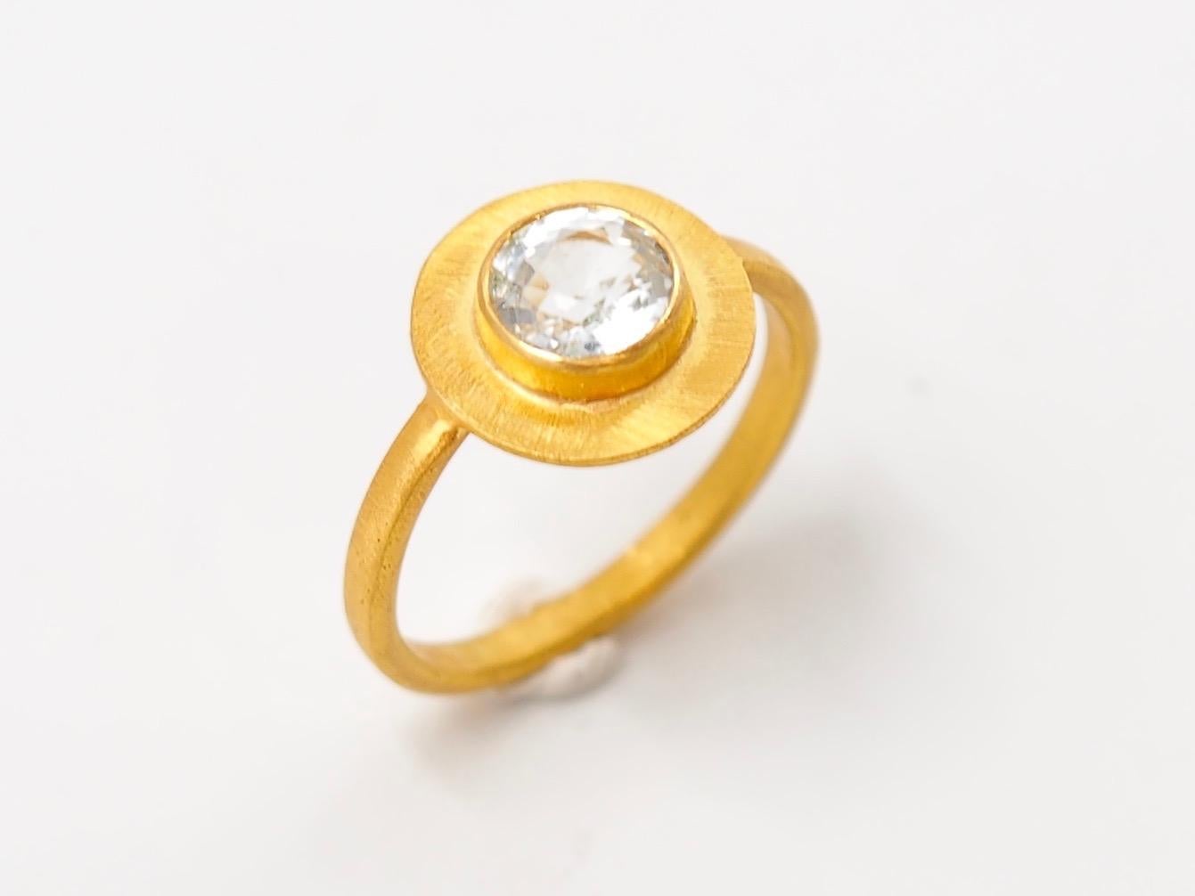 Scrives Sun disk ring is composed of a round aquamarine surrounded by a large gold disk of 22kt gold which is brushed like a sunshine. 
This ring exists also with a pink tourmaline stone.

The stone is a natural untreated aquamarine of approx. 1