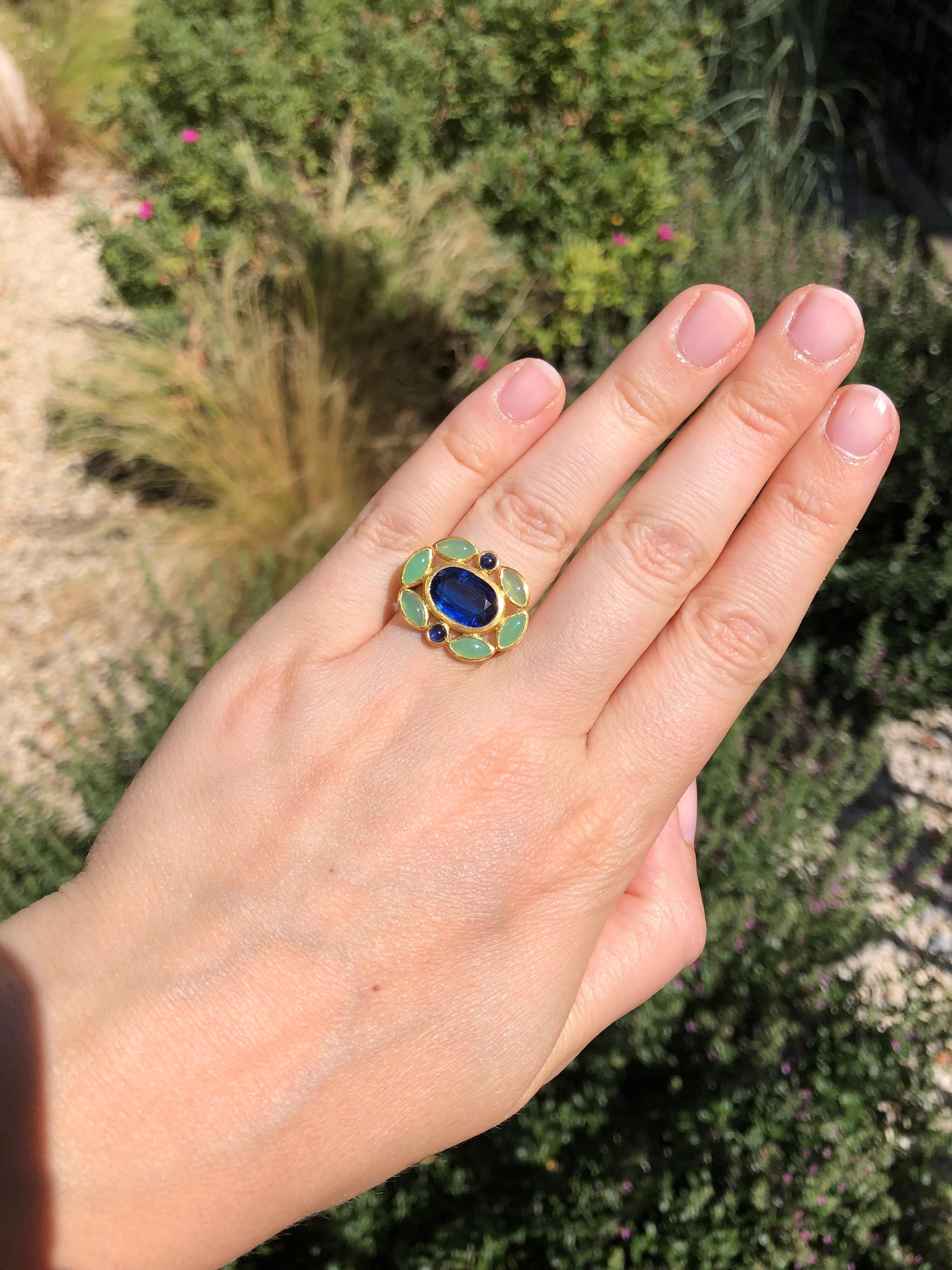 On this one-of-a kind ring by Scrives, a kyanite of 4.63cts is surrounded by 6 navette cabochons of chrysoprase (green natural chalcedony) and 2 blue sapphires cabochons. 
All the stones are set at the same level in 22 kt gold. 
The color of the