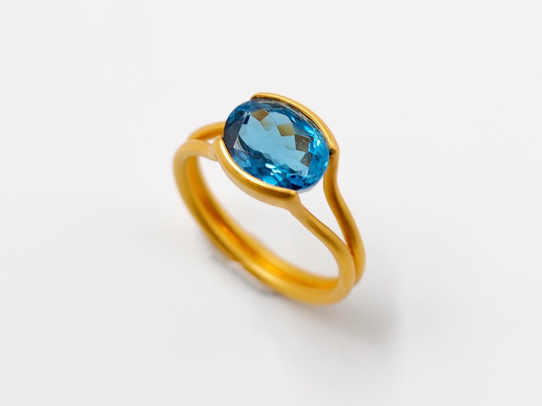 This delicate ring by Scrives is composed of a blue topaz of 3.67 cts. 
The stone is hold by 2 gold lines that form the band. This design allows light to come into the stone from multiple directions and put into highlight the stone. 
This ring
