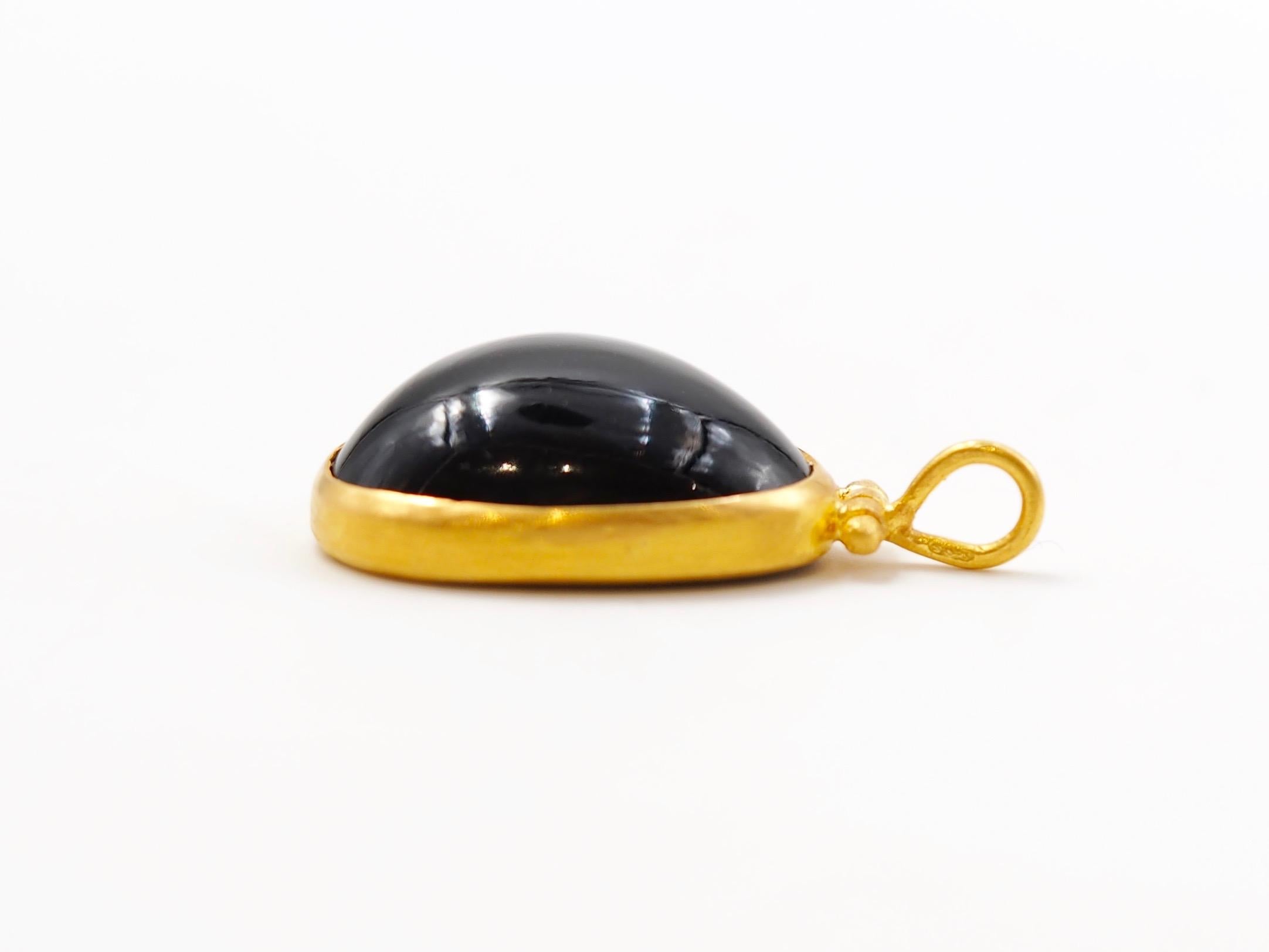 This pendant is composed of a large onyx cabochon of 18.4 cts. 
The top part is a swivel-hook with a large ring to allow any chain. 

This one-of-a-kind pendant is handmade with 22kt mat finish gold. After wearing the jewellery for sometime, the