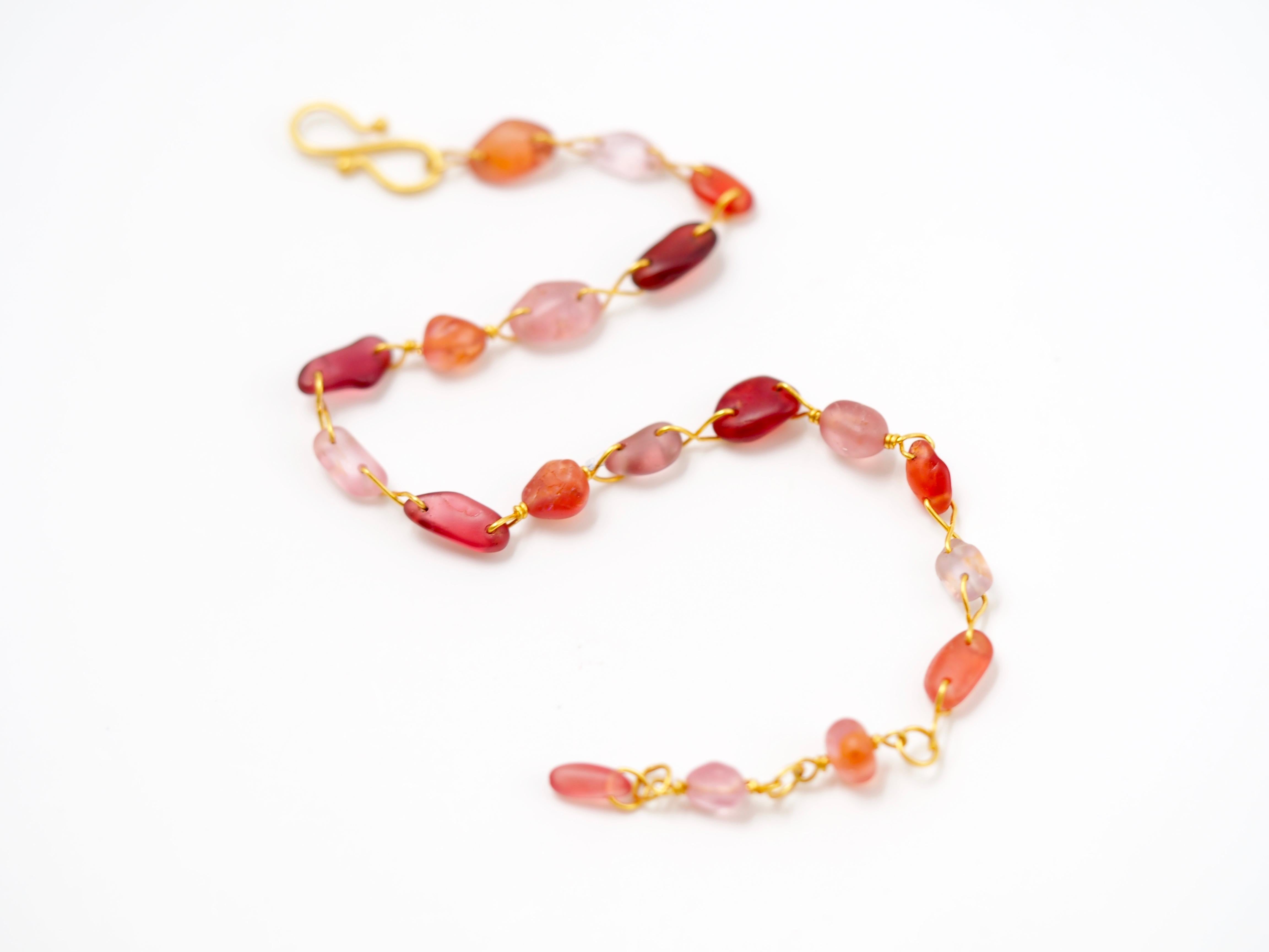 The beads of this bracelet by Scrives are made from natural polished spinels. They all show different shapes and colours in the same tone of orange and red. 
These stones have been found this way in Myanmar rivers. They have been naturally polished