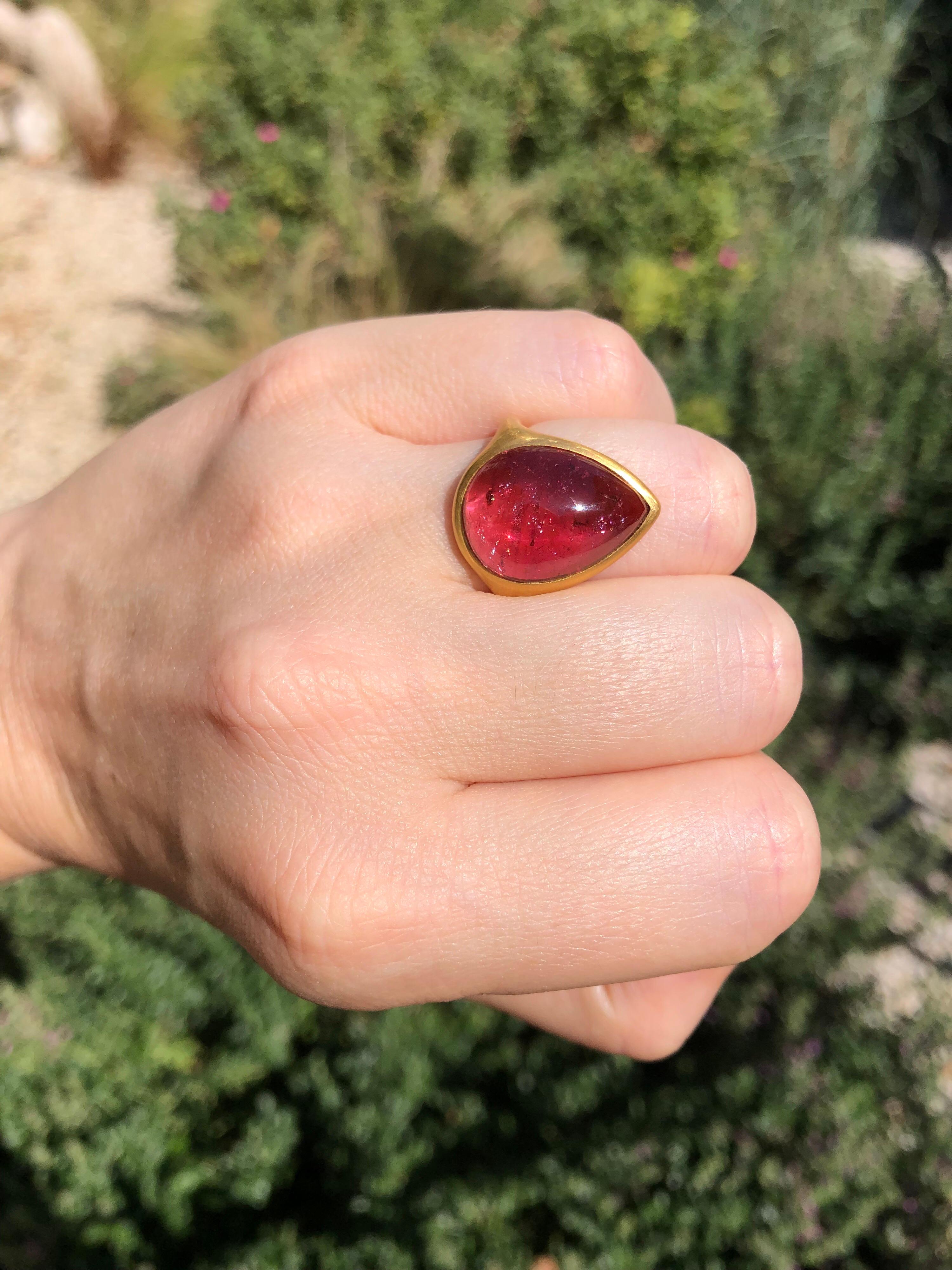 This modern ring by Scrives is composed of a large Pink/red tourmaline cabochon of 13.11cts set in 22kt gold. The tourmaline has very interesting natural inclusions some with darker red colour and others with shinny & rainbow effects which