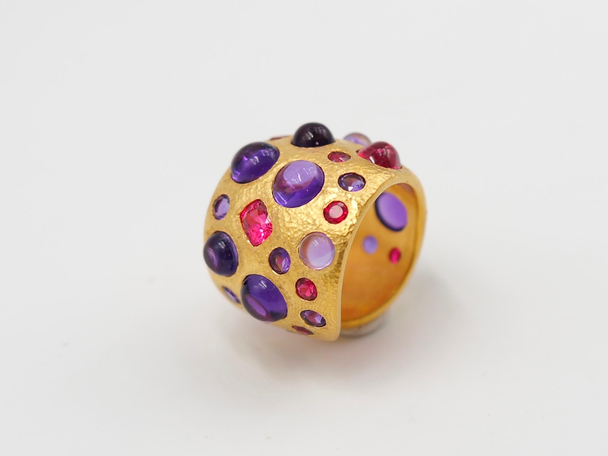 This modern Band ring by Scrives is hand-hammered and set with:
- 2 natural red spinels (cushion shape), 
- 1 natural red spinel cabochon, 
- 8 amethyst cabochons of various sizes, 
- 8 faceted natural red spinels, 
- 11 faceted amethysts. 
The