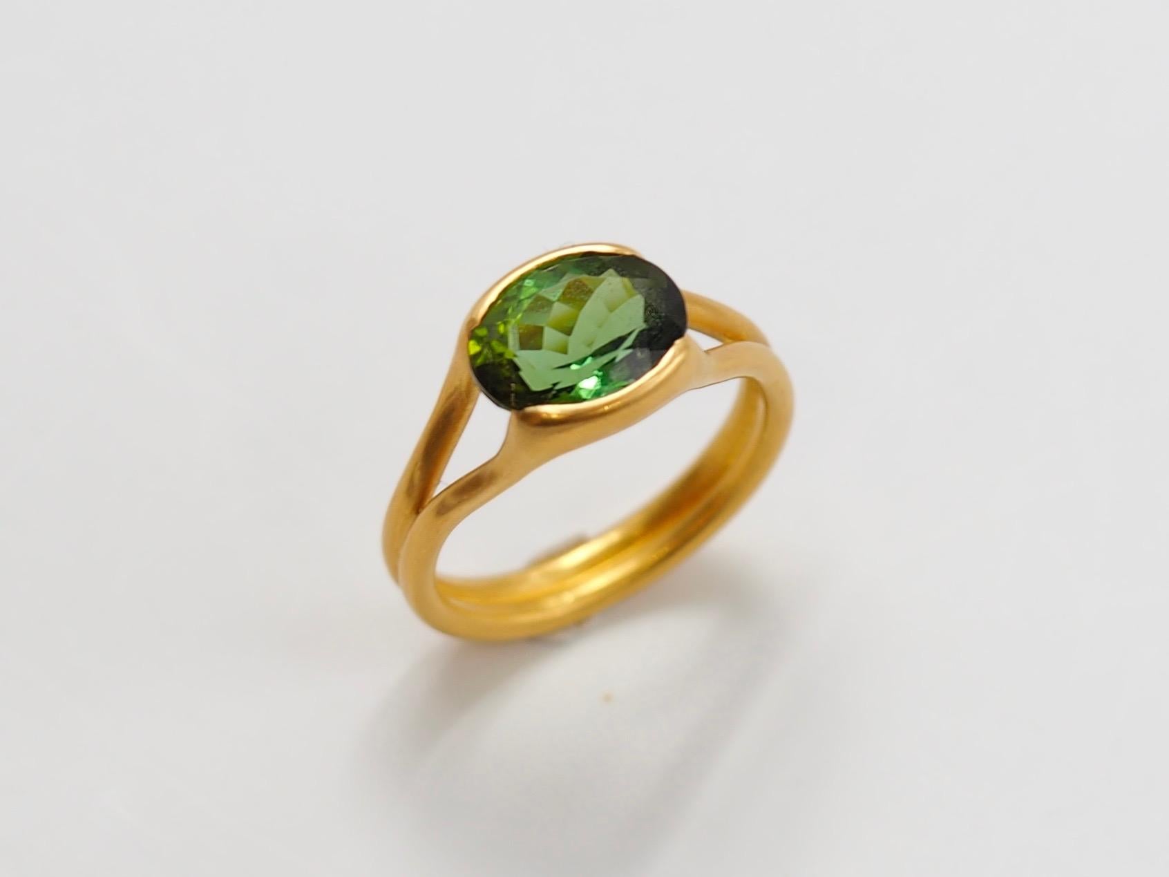 This delicate ring by Scrives is composed of a green tourmaline of 2.65 cts. The tourmaline has 2 hues of green, the central colour is pure green and the side colours of the stone is yellowish green. 

The stone is hold by 2 gold lines that form the