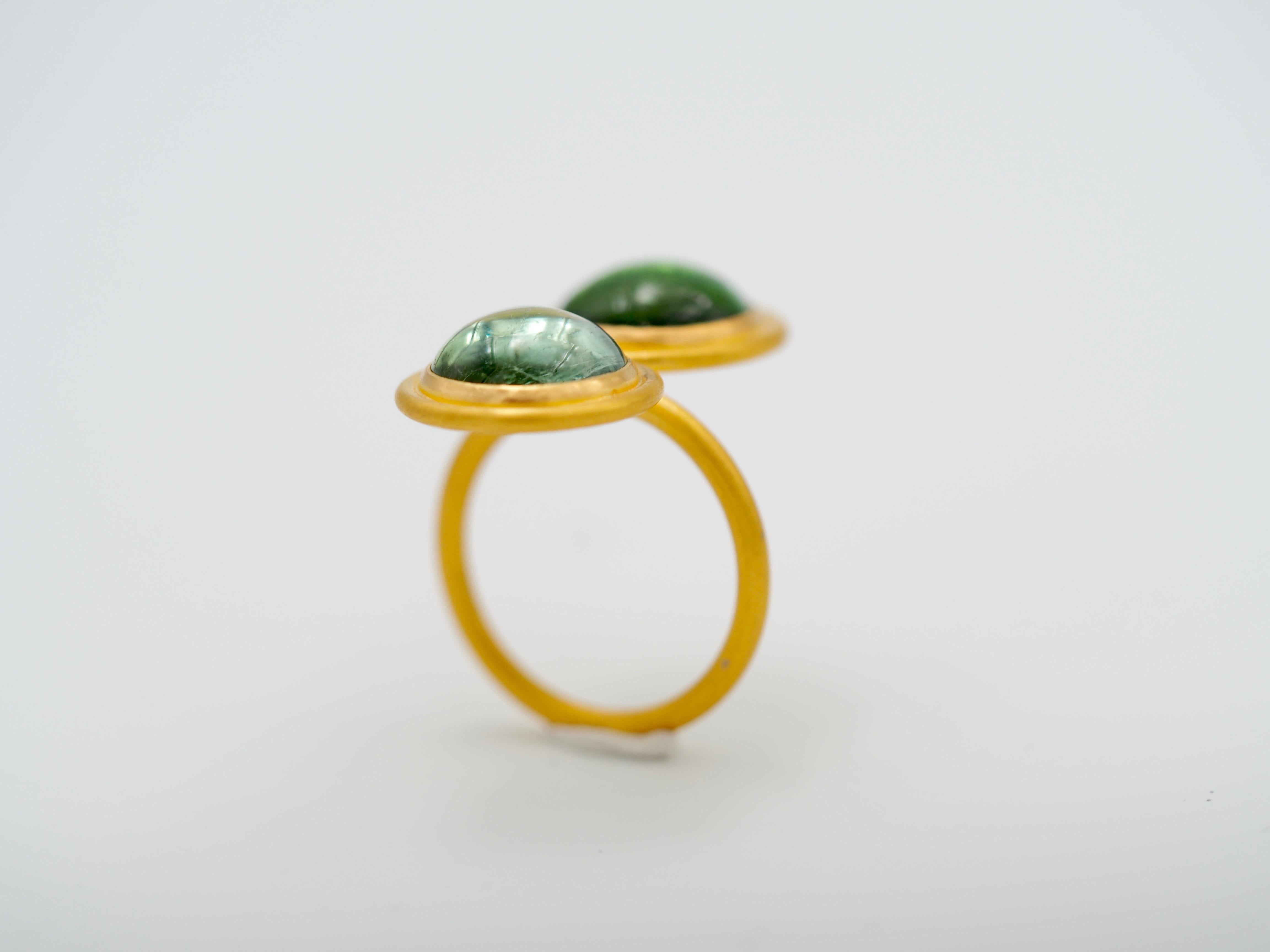 This 8 figure modern ring by Scrives is made with 2 large green tourmalines (12mm rounds, total weight: 10.64cts), one in light green and the other one in darker green. 
The stones exhibit visible natural and typical inclusions. The stones are