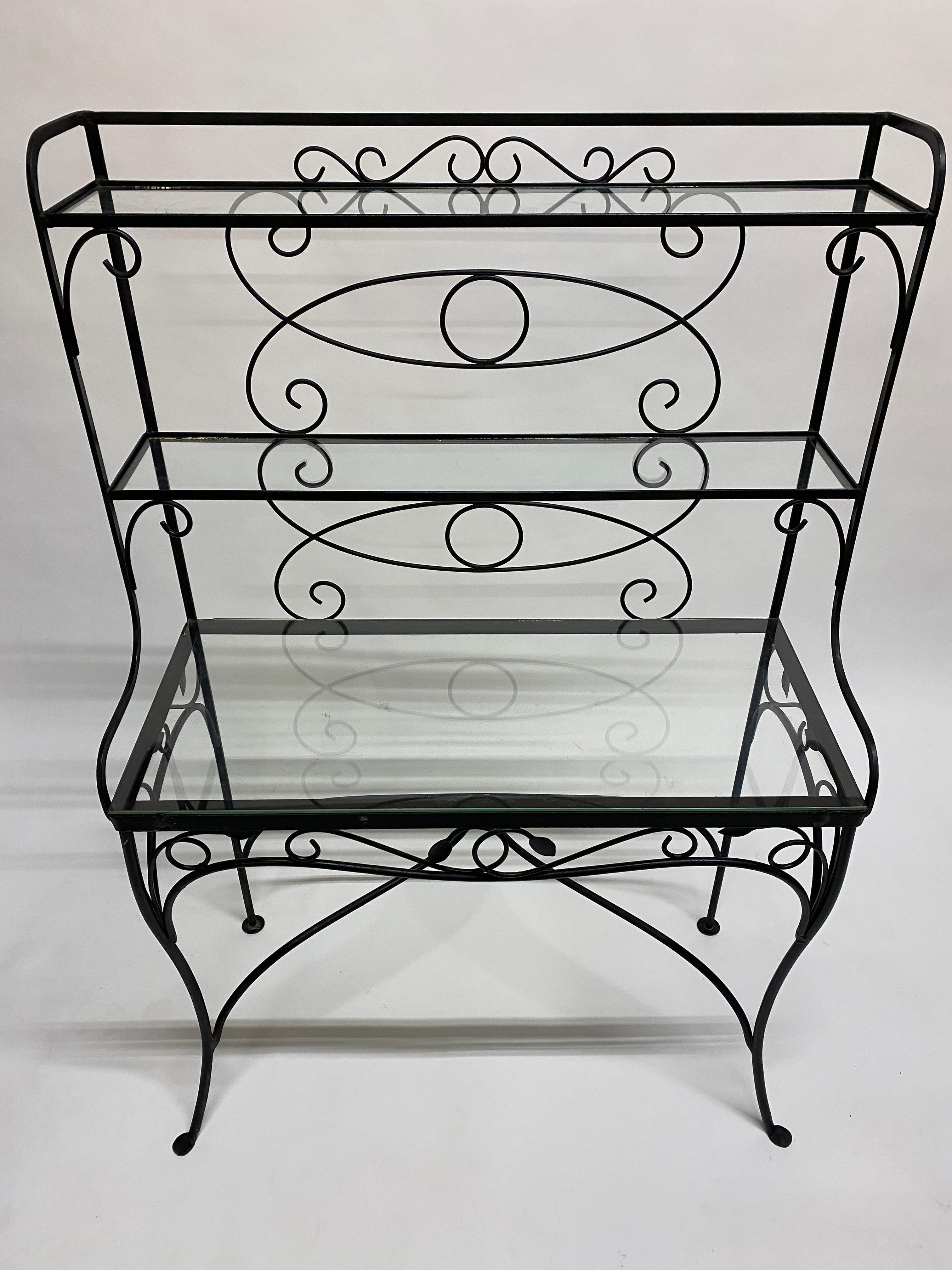 Mid-20 Century designed scroll and leaf iron and glass step back etagere. Three glass shelves and can be used either indoors or out. Fine delicately scrolled iron work with leaf accents in the manner of Woodard or Slaterini outdoor