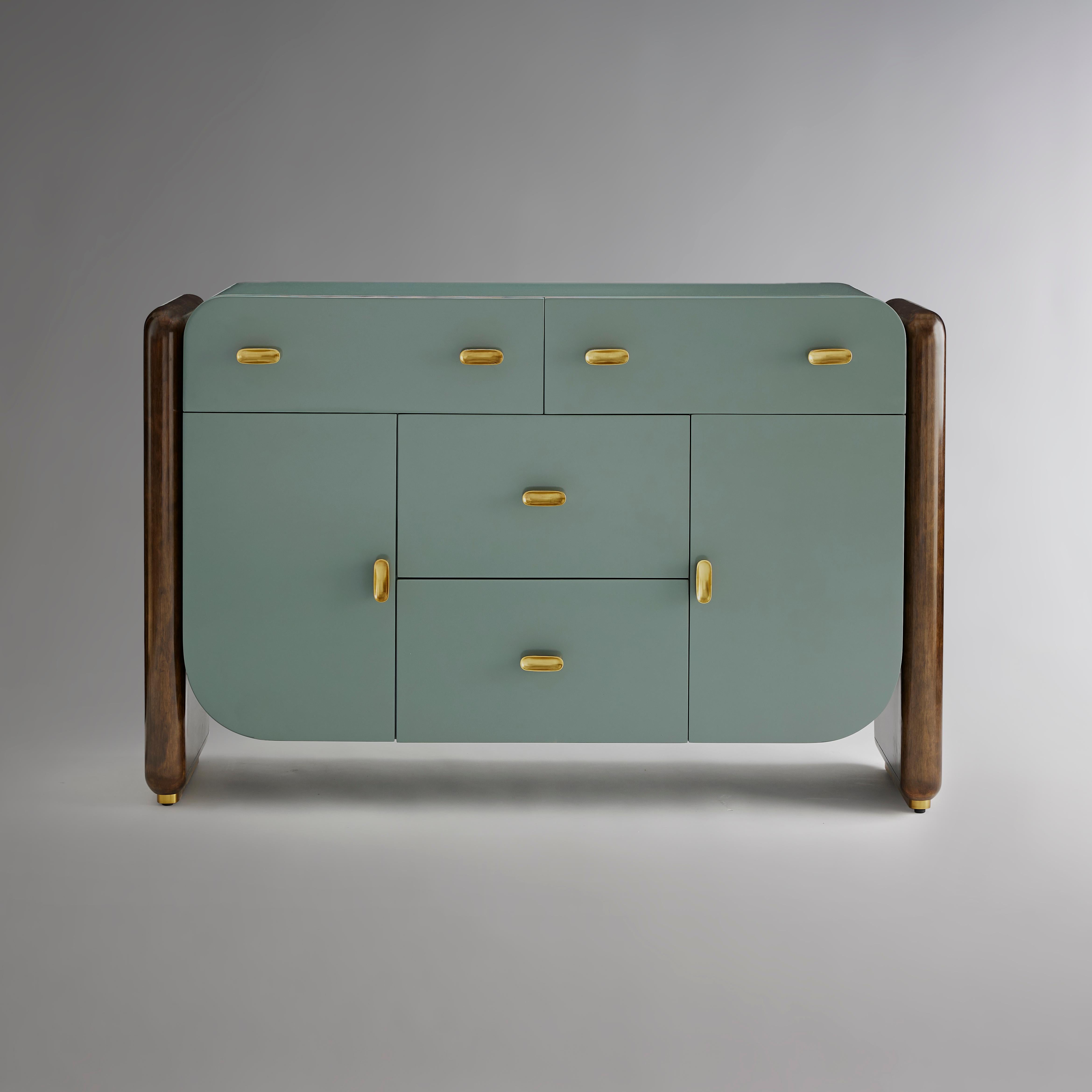 Elegantemente curvo e ricco di dettagli raffinati, il buffet è sorretto da due lati in eucalipto con una ricca finitura marrone medio e da zoccoli in ottone brunito. I tiretti in ottone a forma di pillola sono sagomati a forma di pillola concava,