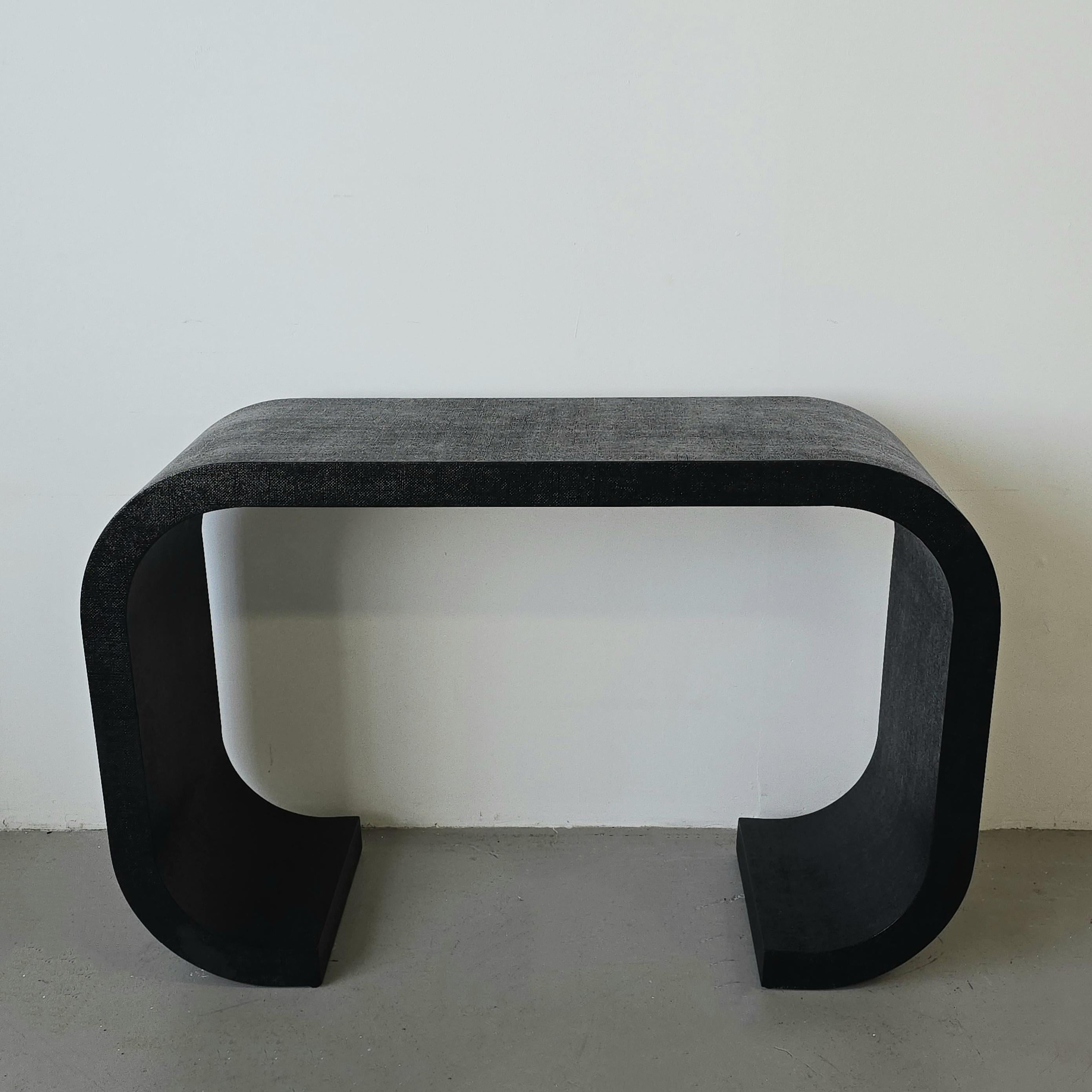 Scroll console table in grasscloth. In the style of Karl Springer. The stunning shape makes it a hard to find piece that is beautifully curved. The top of the table has a waterfall effect on the edges which are followed by legs that scroll inwards