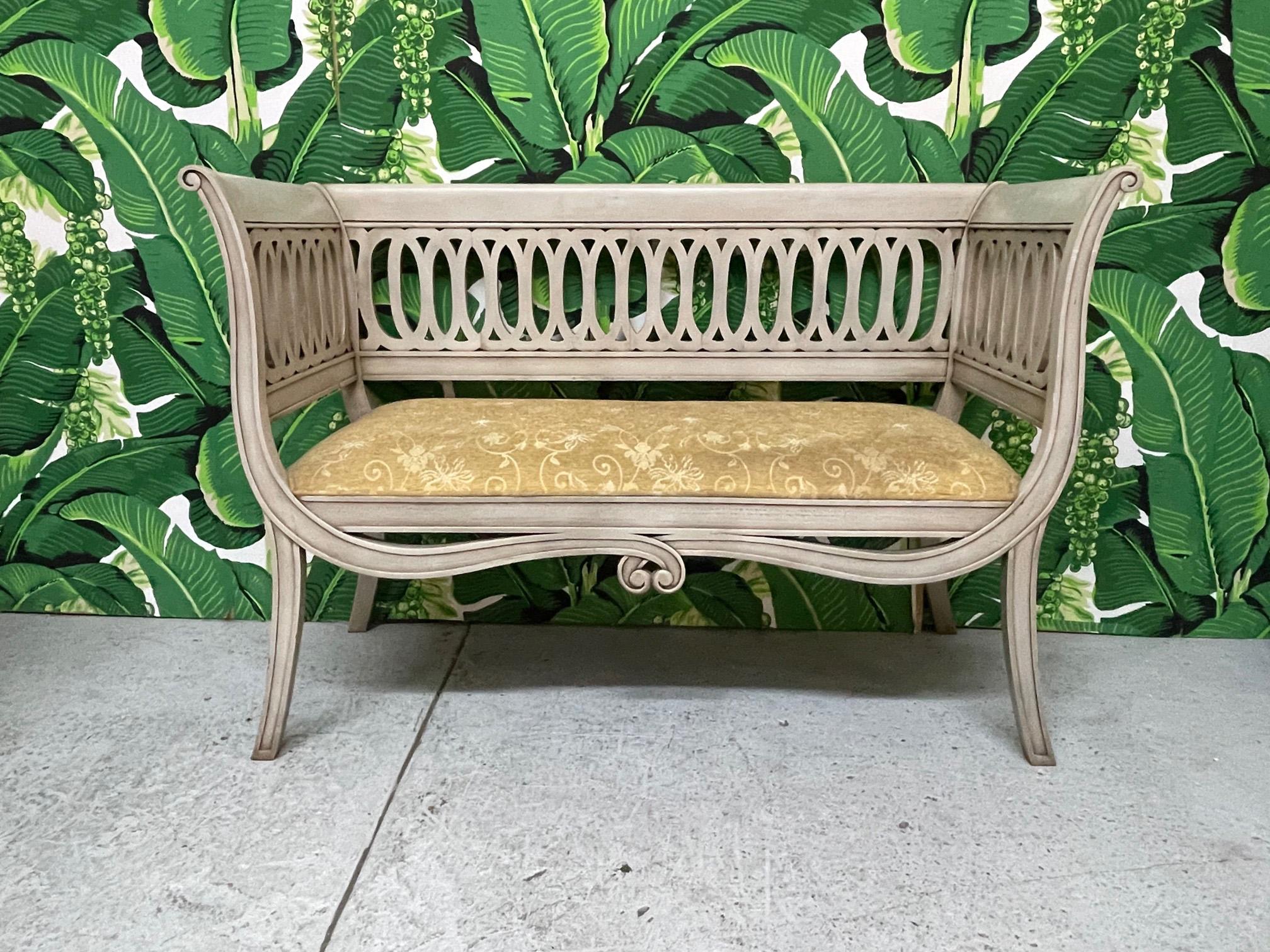 Regency style bench features a scrolled frame and sabre legs. Upholstered in a vintage tone on tone fabric. Finish appears to be original. Good condition with imperfections consistent with age. May exhibit scuffs, marks, or wear, see photos for