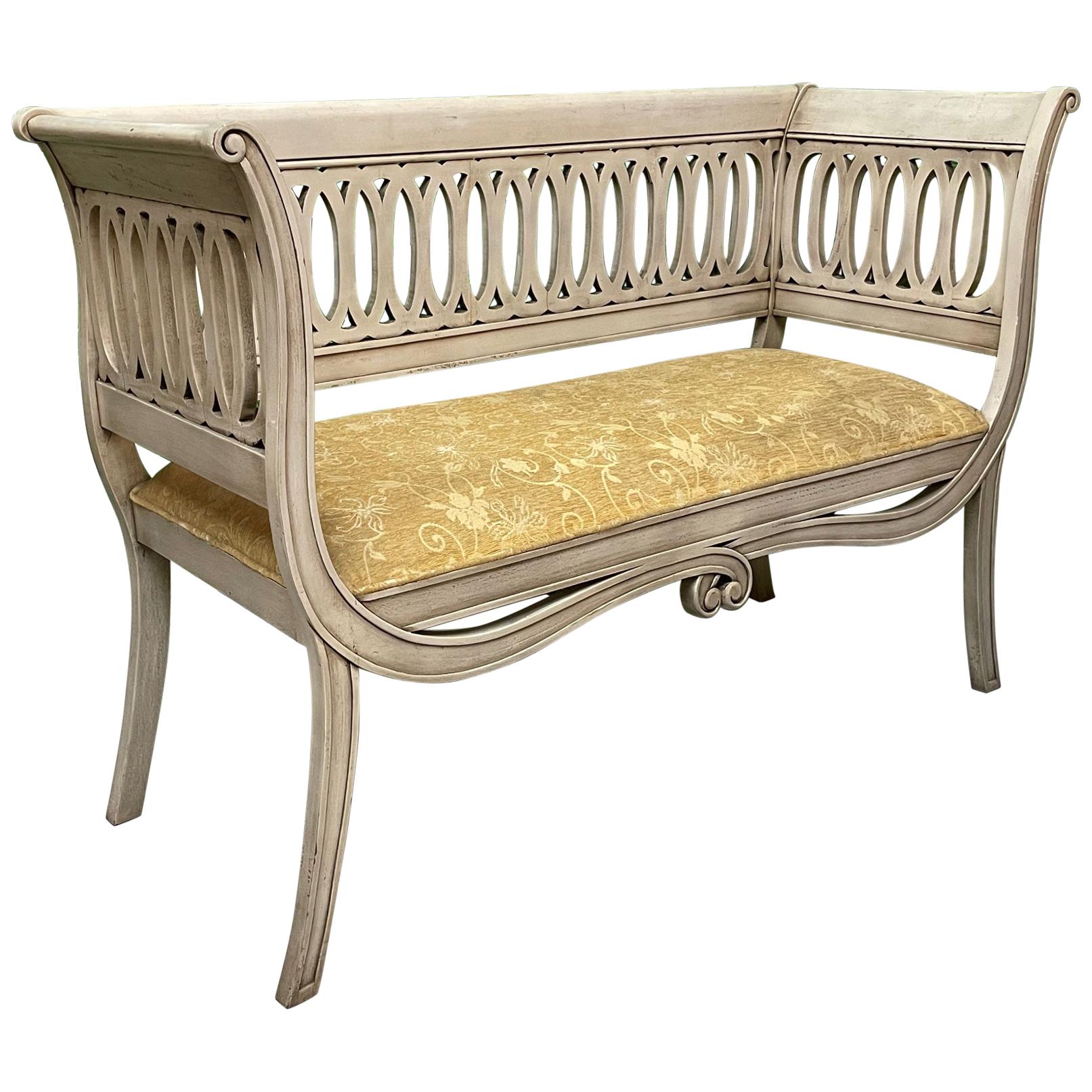 Regency style bench features a scrolled frame and sabre legs. Upholstered in a vintage tone on tone fabric. Finish appears to be original. Good condition with minor imperfections consistent with age.