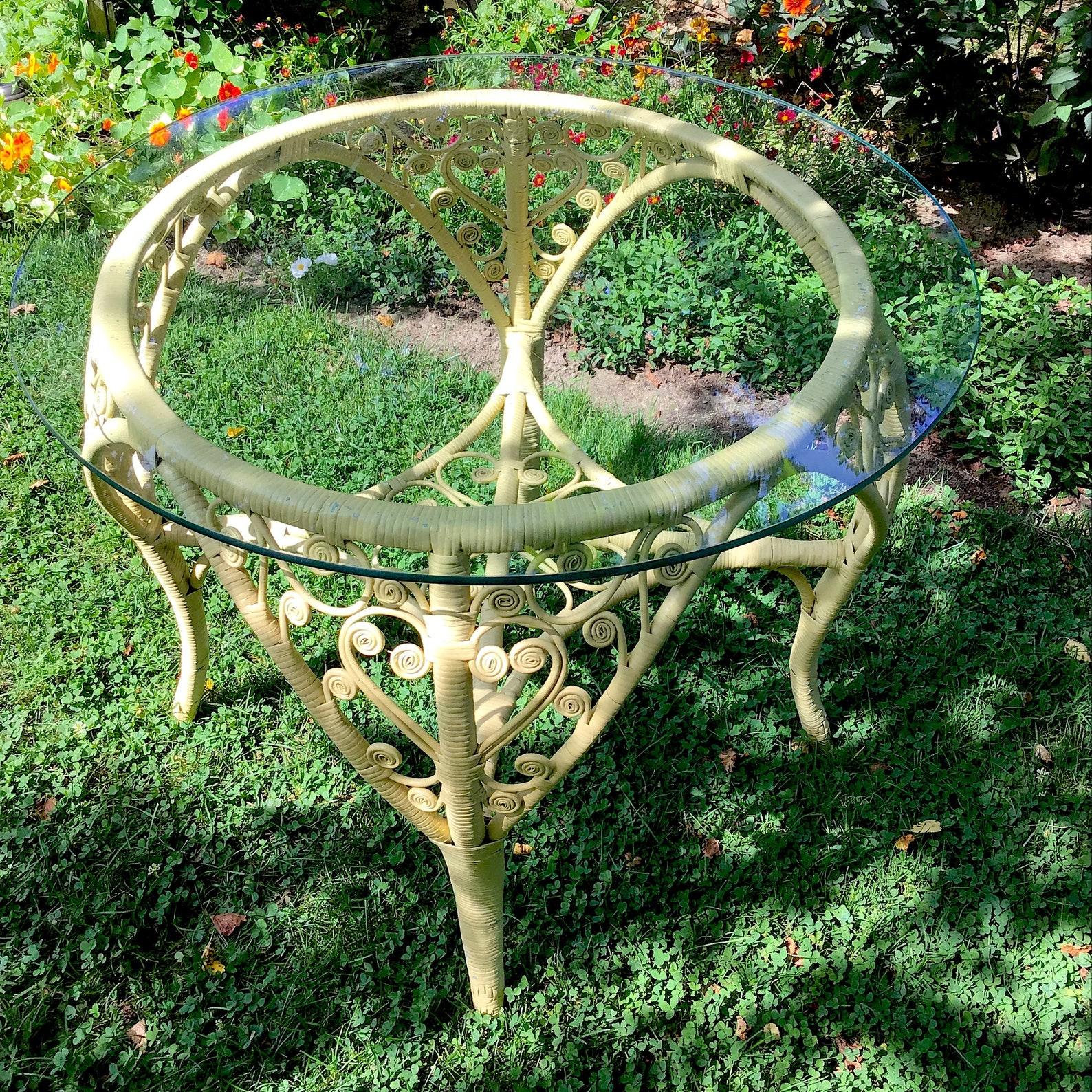 A yellow scroll wicker table with glass top, boho, eclectic, heart shaped wicker.
The patio table measures 30
