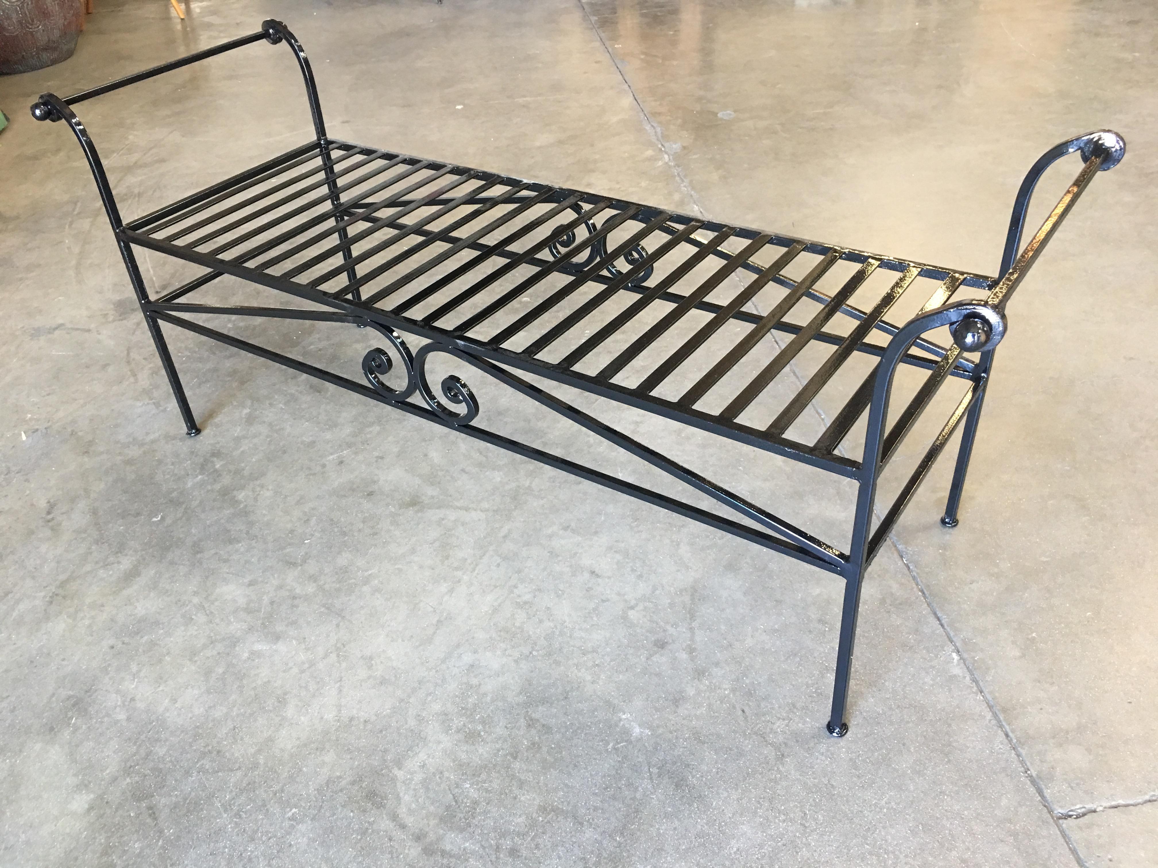 Vintage heavily constructed black wrought iron lounge, bench with scrolling arms and scrolling accents along the front, circa 1950.