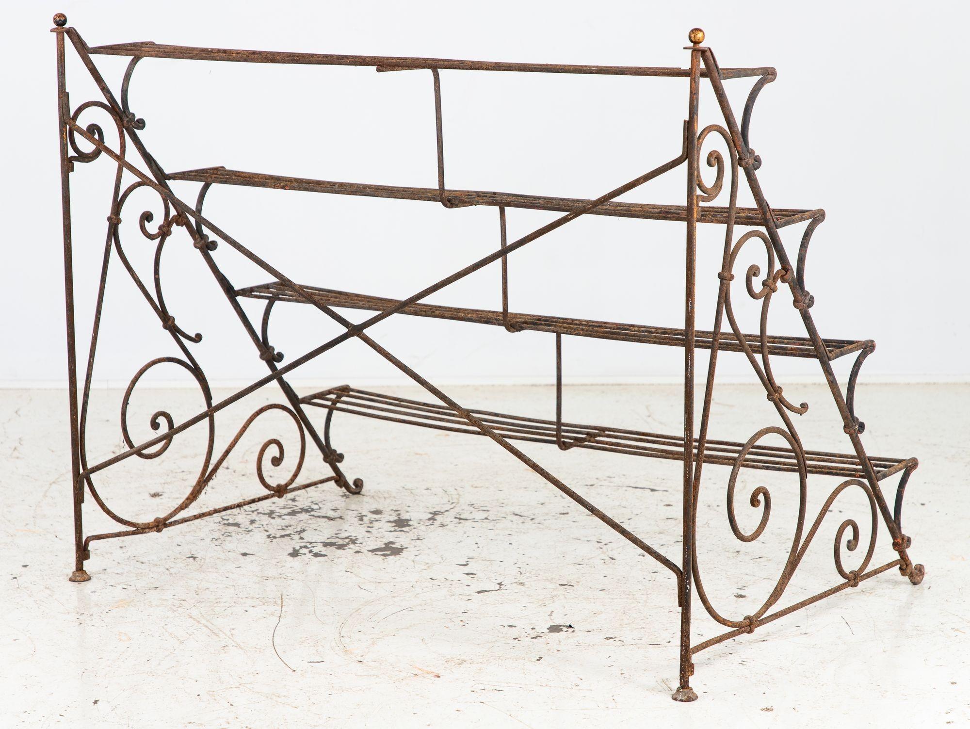 Questo portapiante o étagère in ferro della metà del XX secolo è caratterizzato da un elegante design a quattro livelli con intricate volute. La struttura in ferro, realizzata con precisione, mette in mostra una miscela senza tempo di funzionalità e