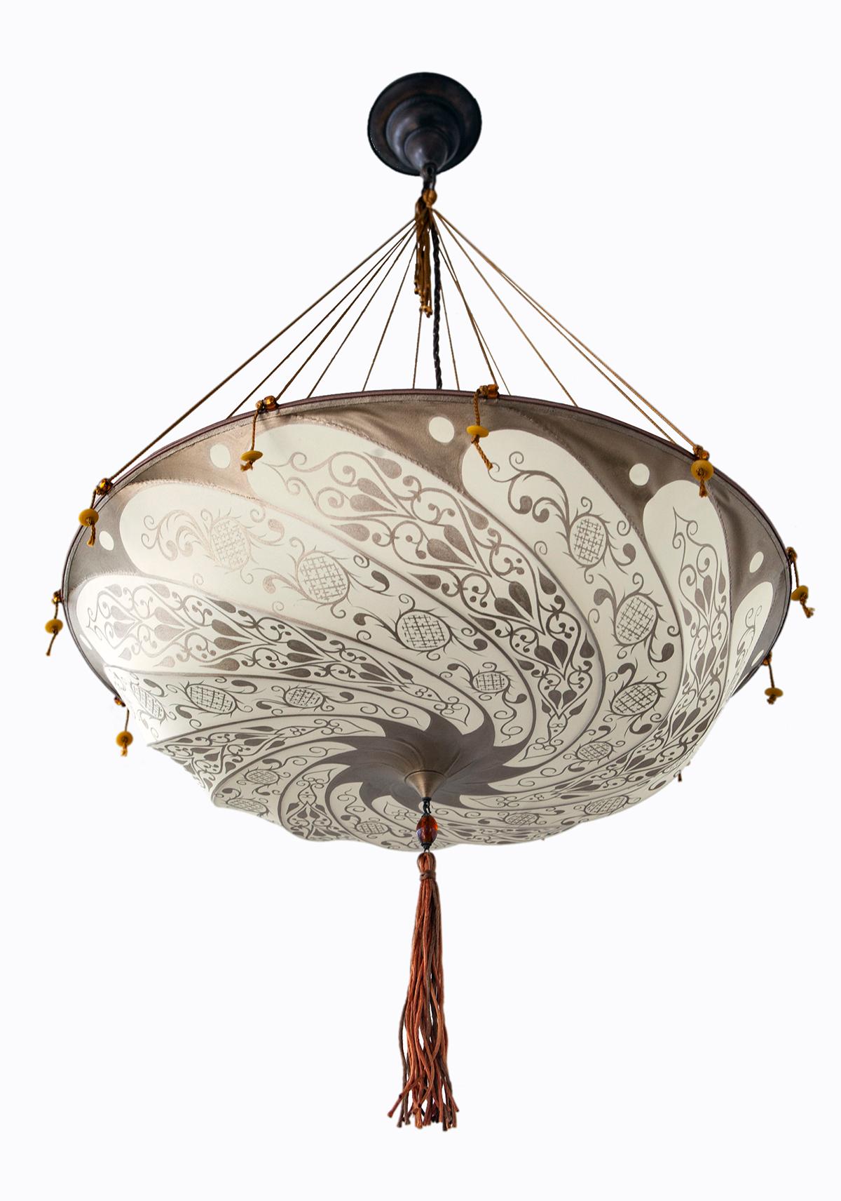 Classic silk Fortuny Scudo Sareceno chandelier with ceiling plate, cords and bead tassel in ivory and pale gold. Murano glass beads decorate each cord. 24” diameter. Excellent condition.
A masterpiece of craftsmanship, this famous silk lamp has