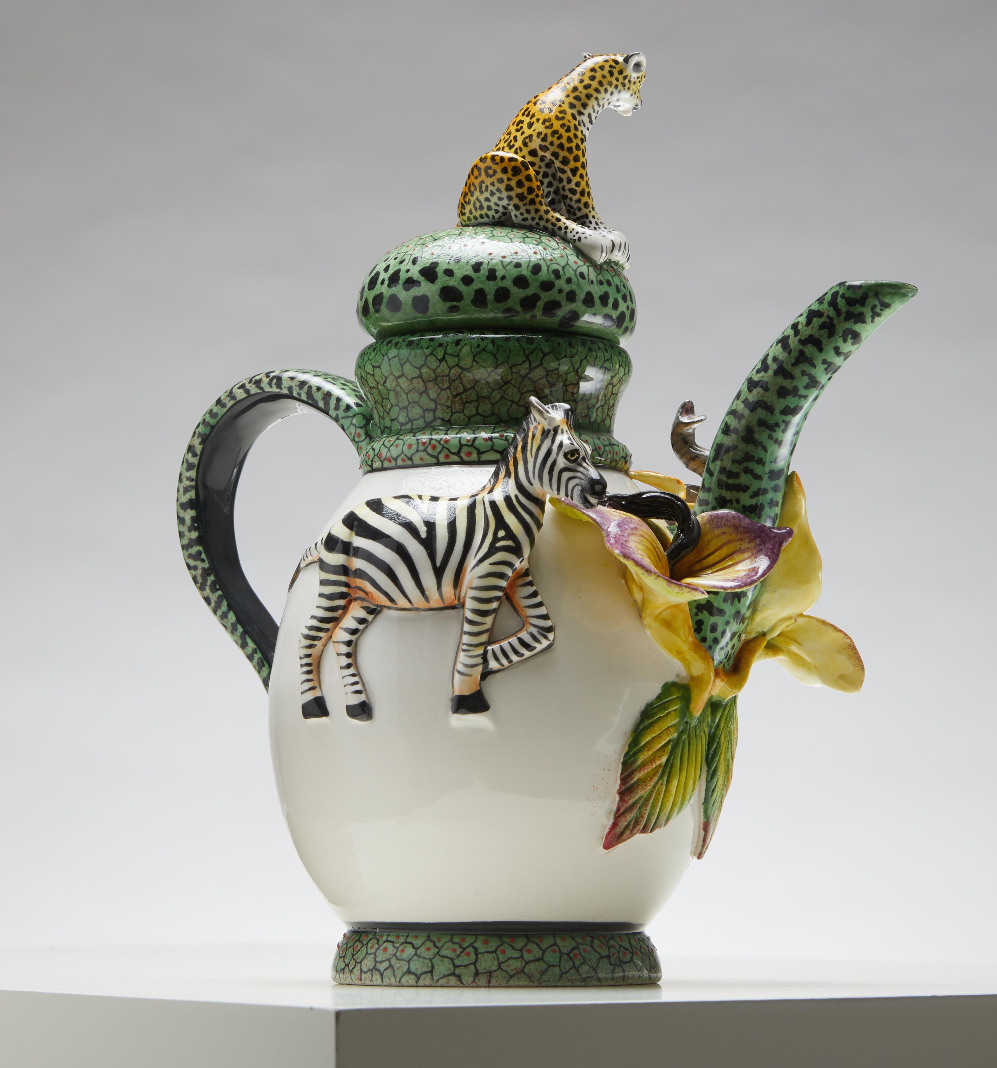 Ti presentiamo la teiera African Sculpted Animal Kingdom, un pezzo mozzafiato che celebra la maestosa fauna dell'Africa. Questa teiera unica è realizzata magistralmente a mano e presenta sculture intricate di un elefante, una zebra e un leopardo,