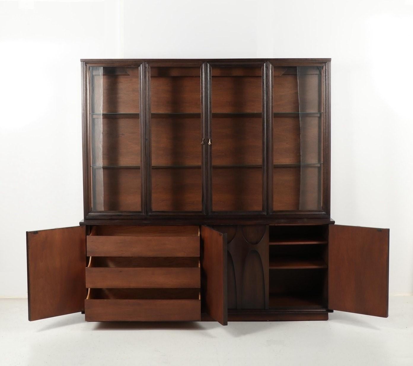 An exceptional Broyhill Brasilia Mid-Century Modern sculpted walnut credenza/sideboard with detachable hutch. It features gorgeous walnut wood grain, with sculpted arches and original pulls. Professionally refinished in dark walnut stain. It offers