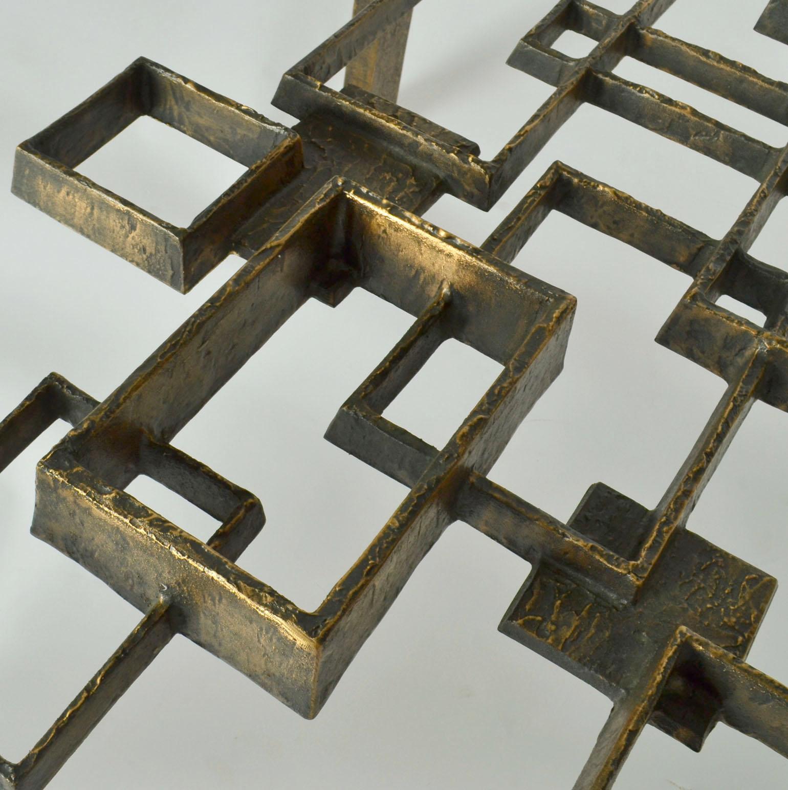This unique sculptural bronze cast coffee table is a work of art. It is a master piece of design and execution by three highly skilled master casters made in the 1970's. The floating forms of interlinking square and rectangular shapes evoke