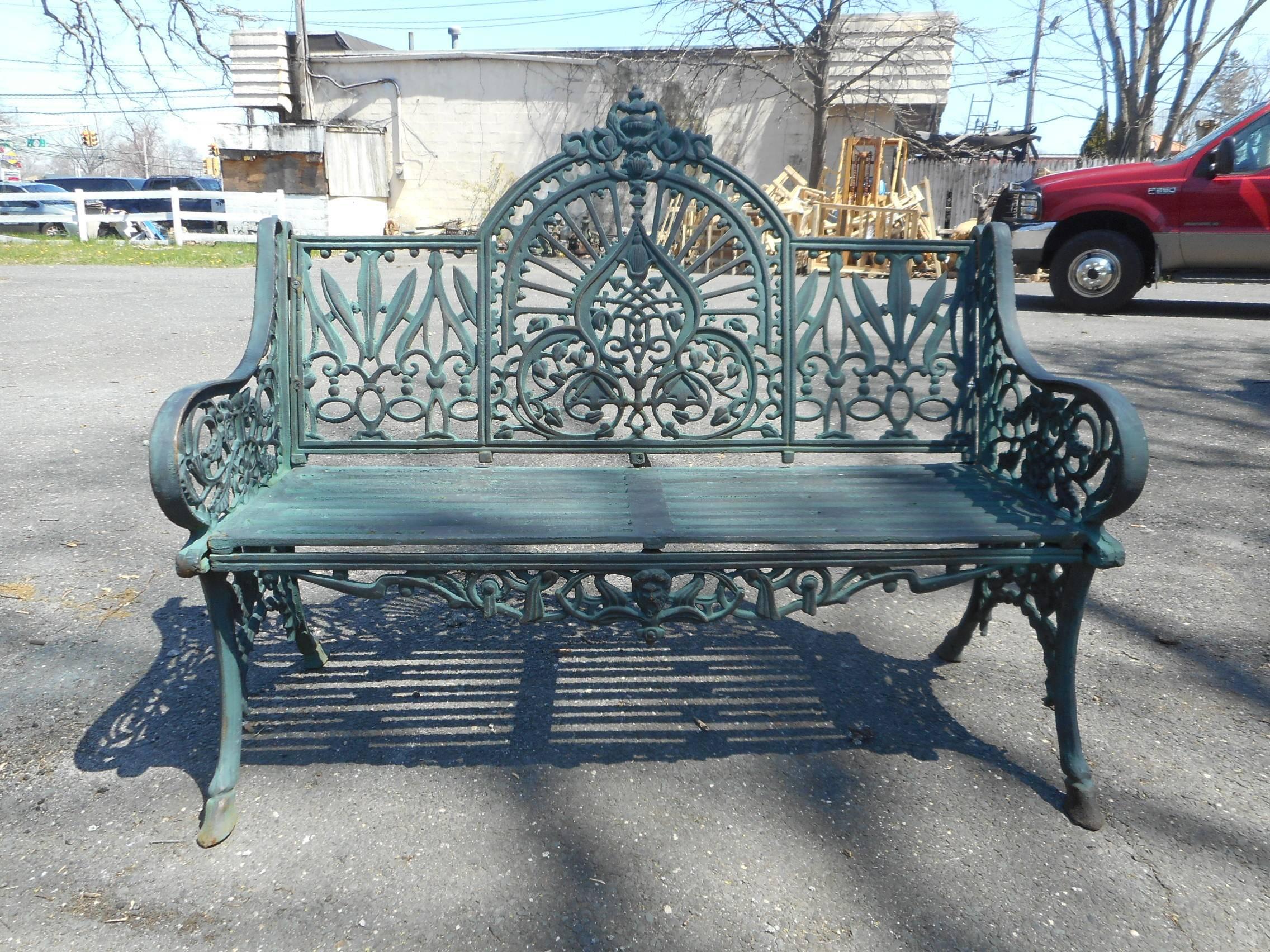 This beautiful cast iron bench features sculpted arm rests, an arched backrest, and a slatted seat. A unique and comfortable design with excellent detail throughout. Splayed legs and a decorative backrest make this piece the perfect addition to any