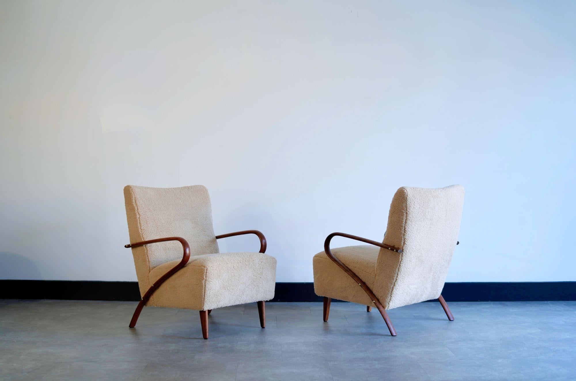 Une superbe paire de chaises longues italiennes vintage, circa 1950, présentant des bras élégamment sculptés en bois de cerisier avec des ferrures décoratives en laiton. Entièrement restauré par Stamford Modern, le bois riche a été méticuleusement