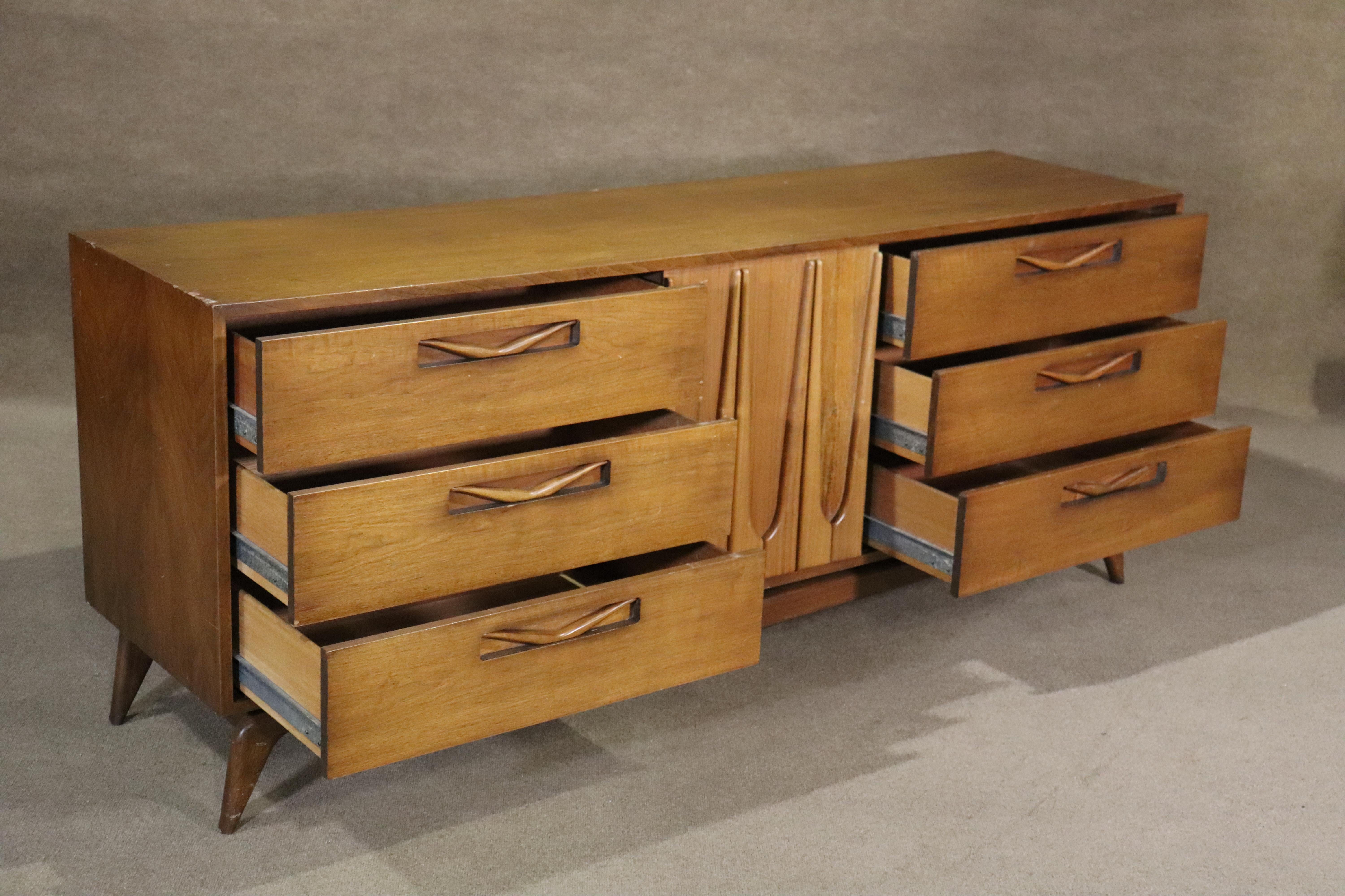 Wonderful Mid-Century Modern dresser with hints of Vladimir Kagan and Broyhill Brasilia in the sculpted wood front and delicate floating legs. Nine total drawers with sliding middle door.
Please confirm location NY or NJ.