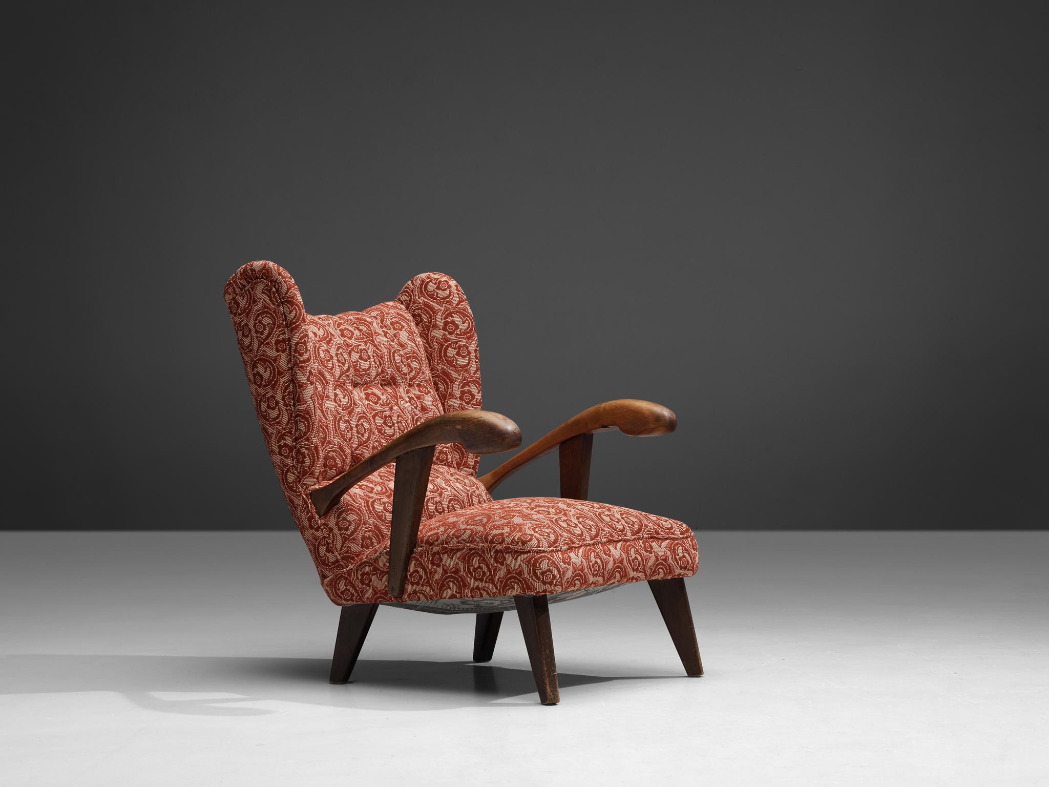 Lounge chair, walnut, fabric, Czech Republic, 1950s. 

This exquisitely crafted lounge chair holds a remarkable construction that showcases sculpted elements evident in its wooden frame and back. The armrests are defined by their bold, curved lines
