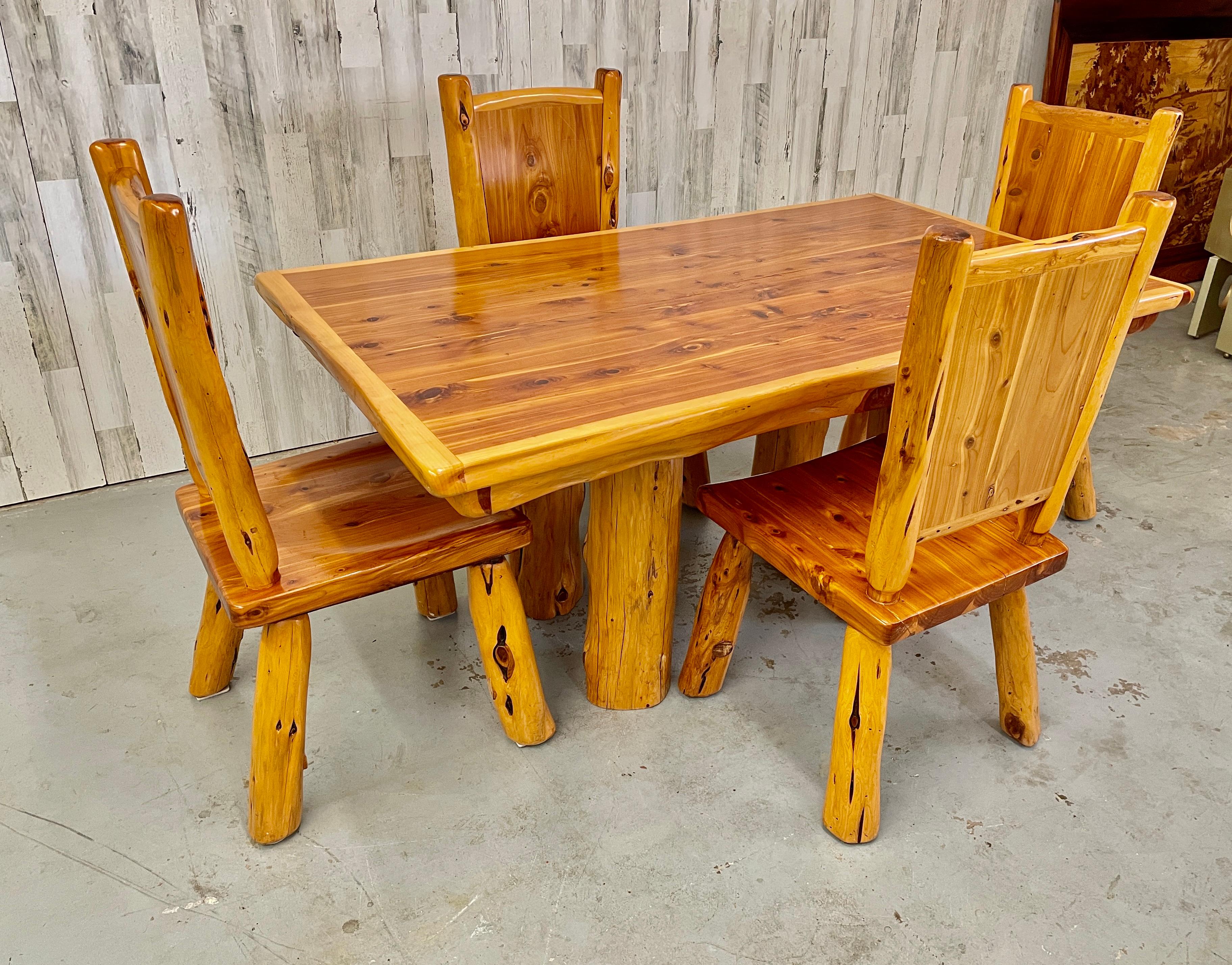 Solid Lodge pole pine table with a scuplted live edge and four sprawled leg chairs 
Very durable for any cabin or lodge.