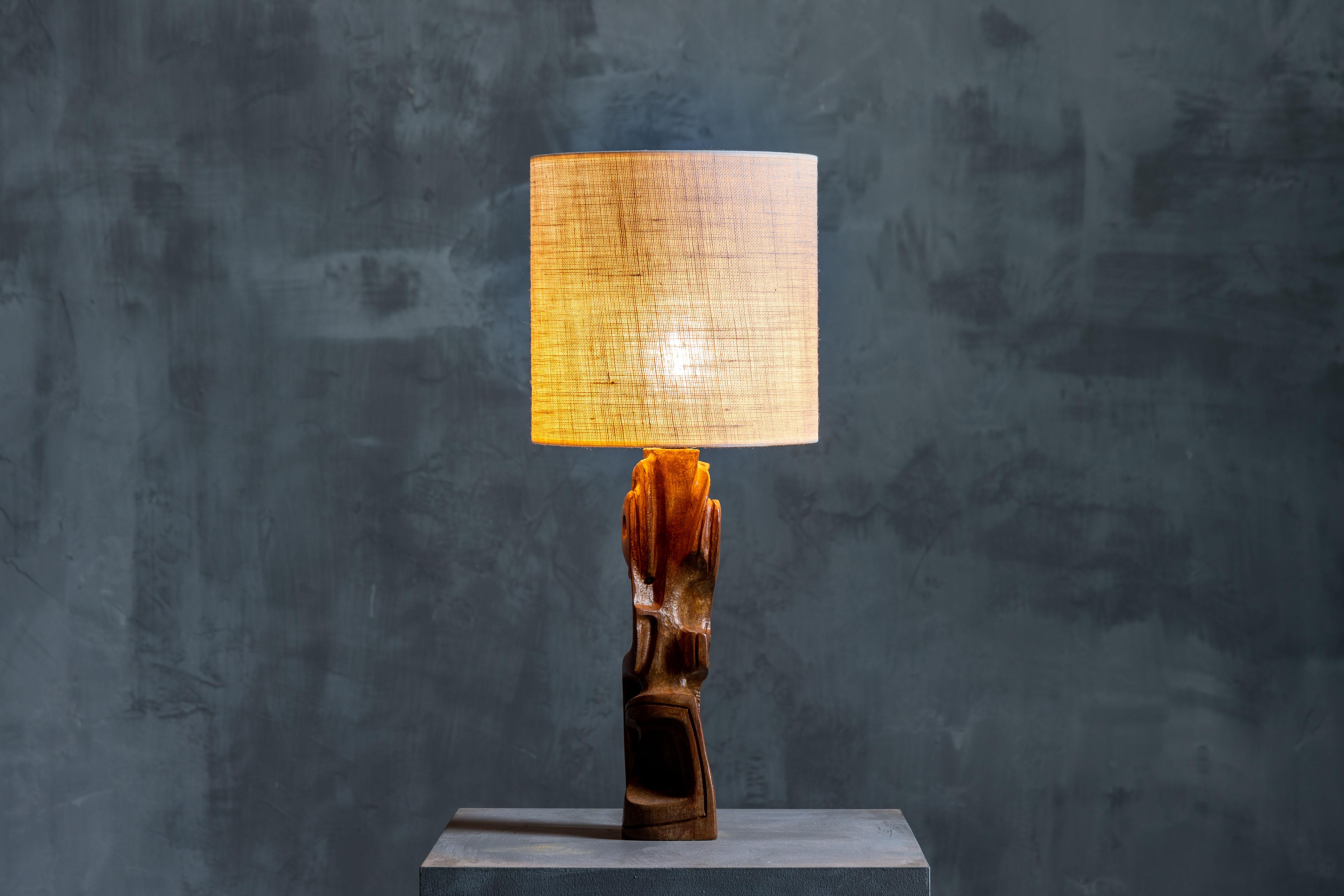 Gianni Pinna's sculpted table lamp from 1970s Italy, crafted from Legno Padouk wood. It showcases a rugged and brutalist aesthetic that captivates the senses. Embodying an era of bold design and artistic expression, this lamp exudes an irresistible