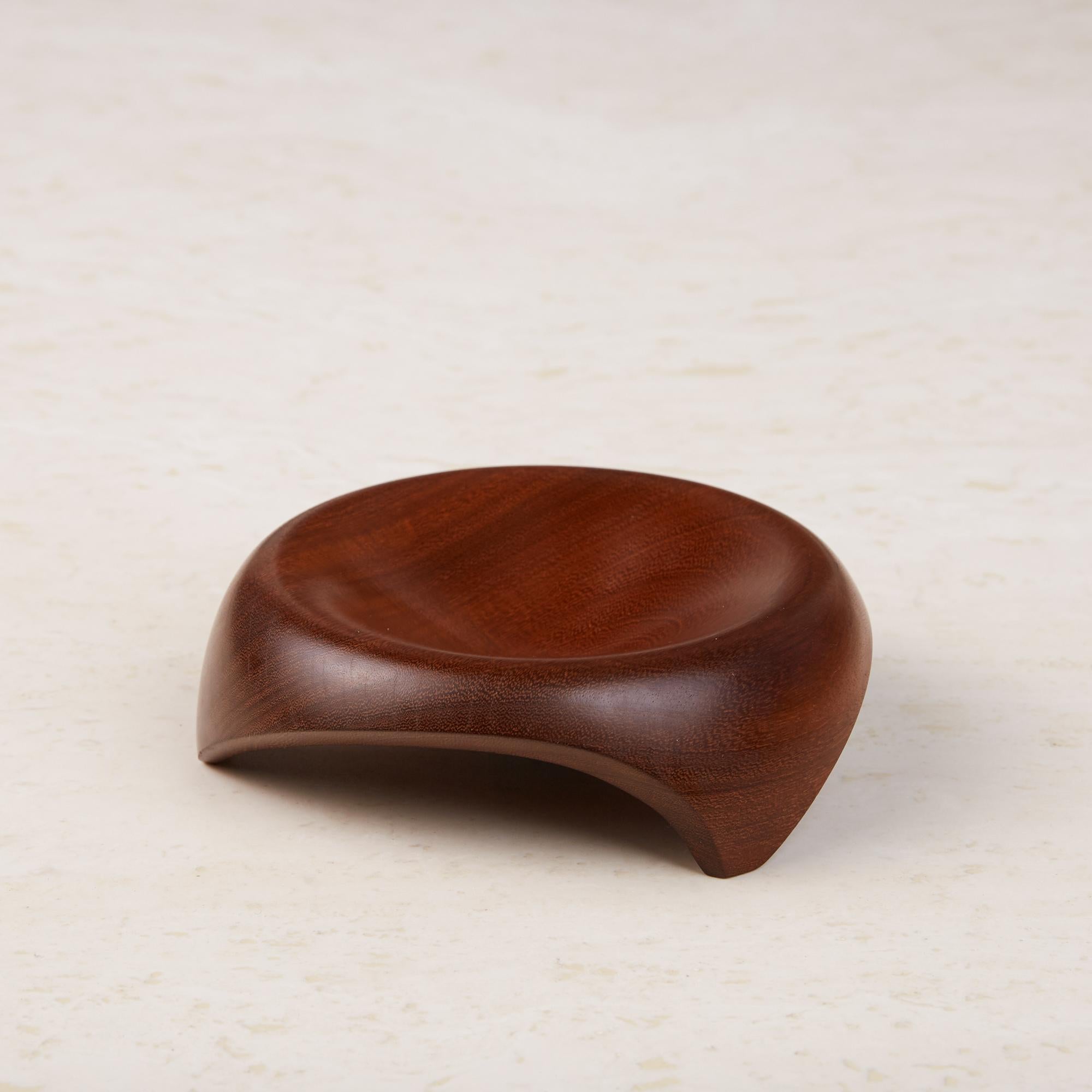 Turned teak wood object with a satin finish that could be used as a catchall dish. The dish has three feet that have been cut from the foot of the dish in a manner that makes it look like it’s in motion.

Dimensions: 5.5