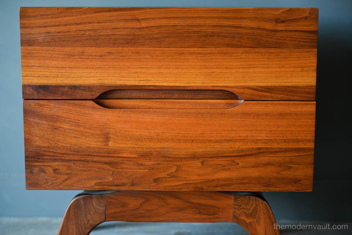 Sculpted walnut nightstand, circa 1965. Solid walnut frame and sculpted splayed leg design. Excellent original condition with cut-out front drawers.

Measures: 22