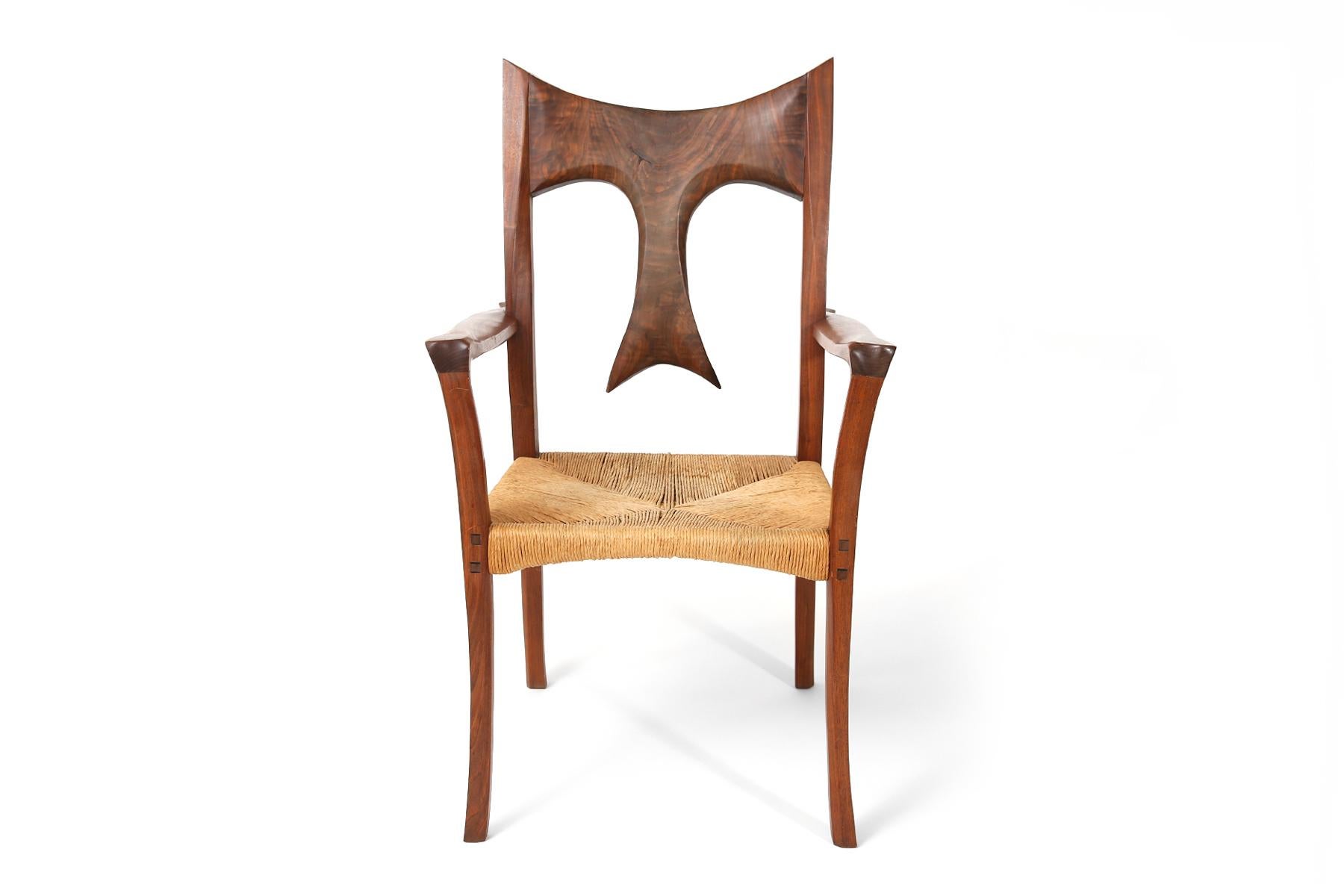 Stunning studio crafted solid walnut and raffia armchair, late circa 1970s. This sculptural example has an unusual handcrafted back, beautifully formed arms and masterful joinery.