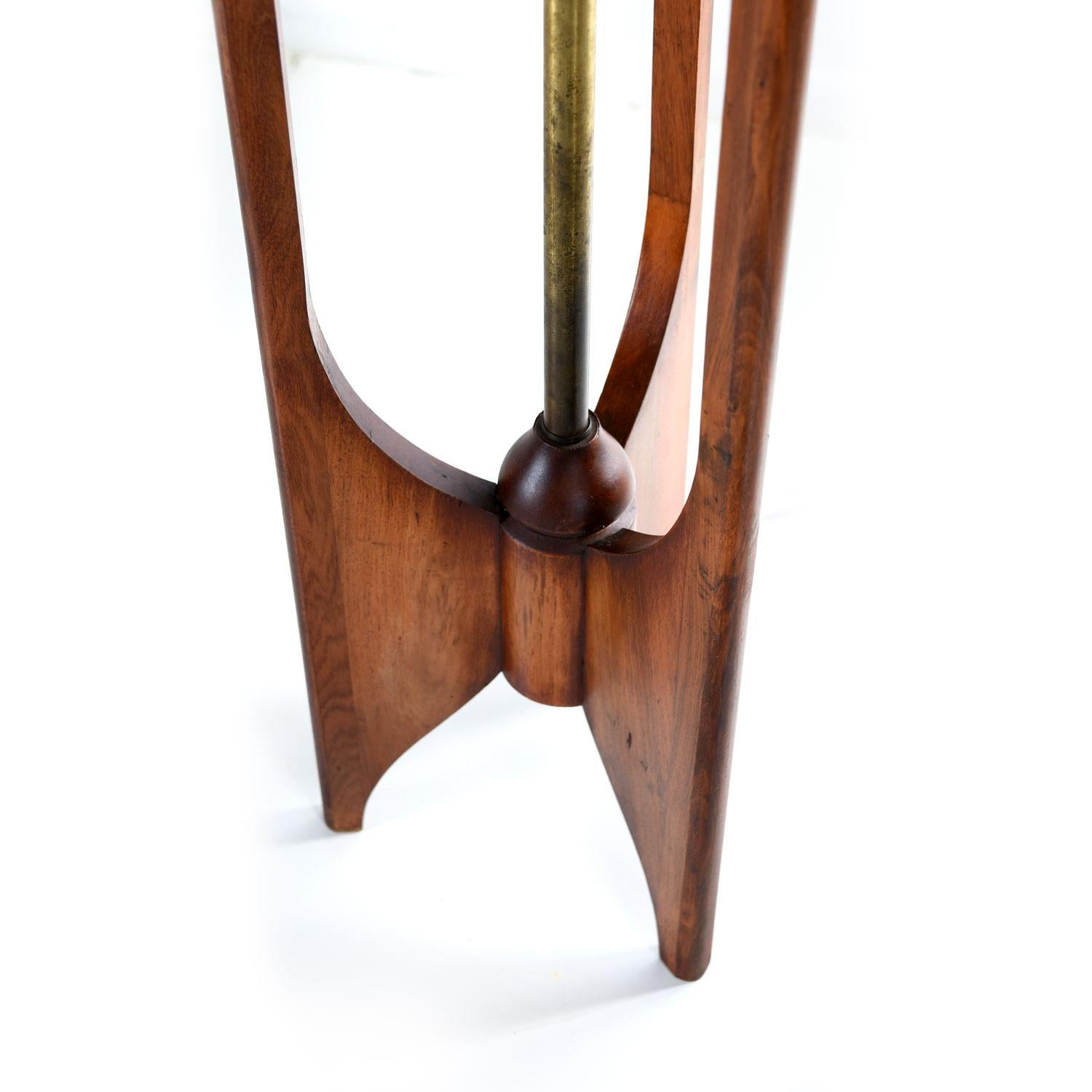 This piece looks very similar to others made by Modeline, but we had no luck identifying this style 100%. Walnut wood tall table lamp, circa 1950s. Three sculpted walnut spines reach upward towards the shade. The shade creates a warm amber glow that