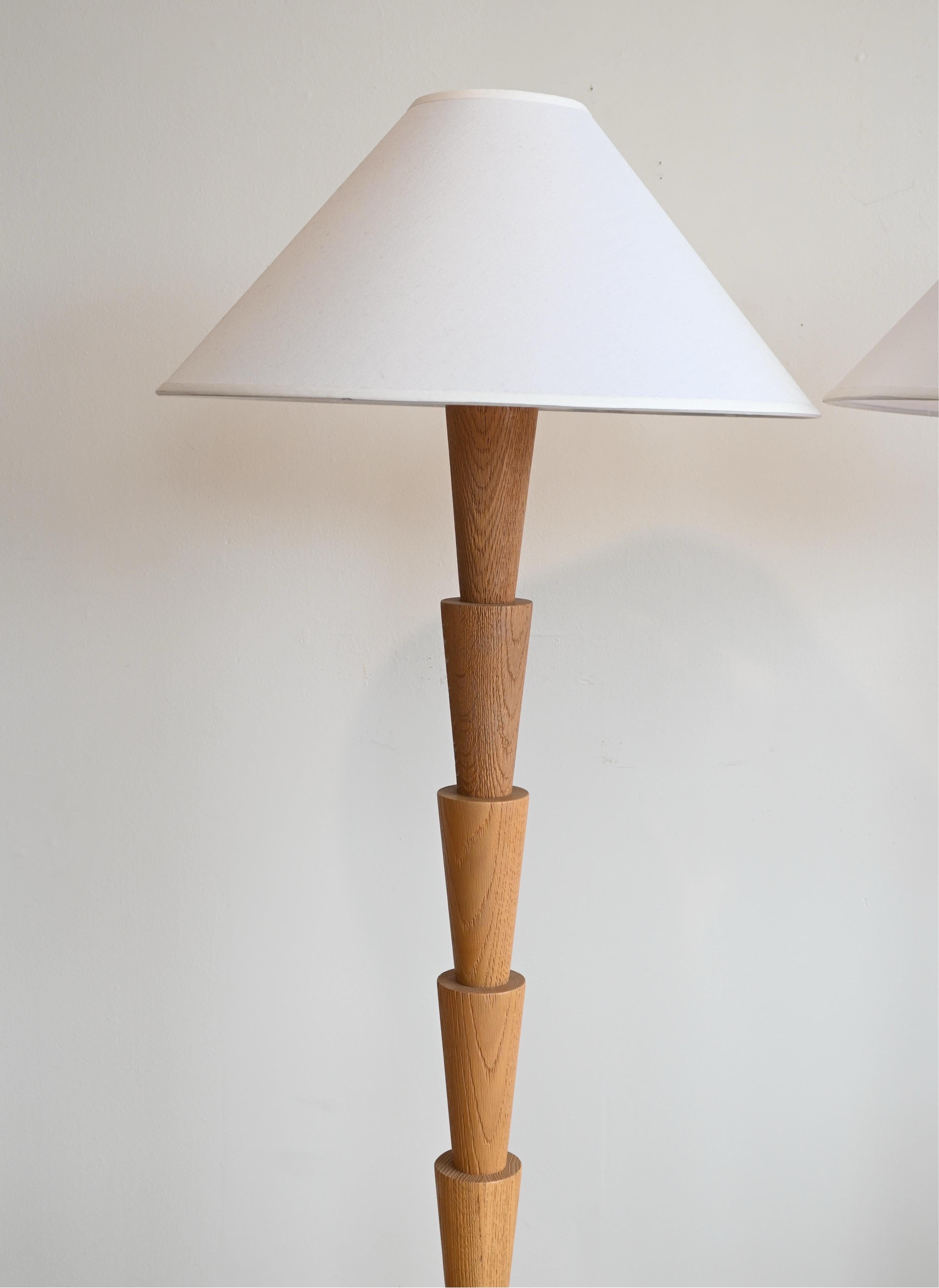 Paire de lampadaires de grande taille. Corps et base en chêne blanc tourné et sculpté, avec des teintes blanches modernes et contemporaines. 