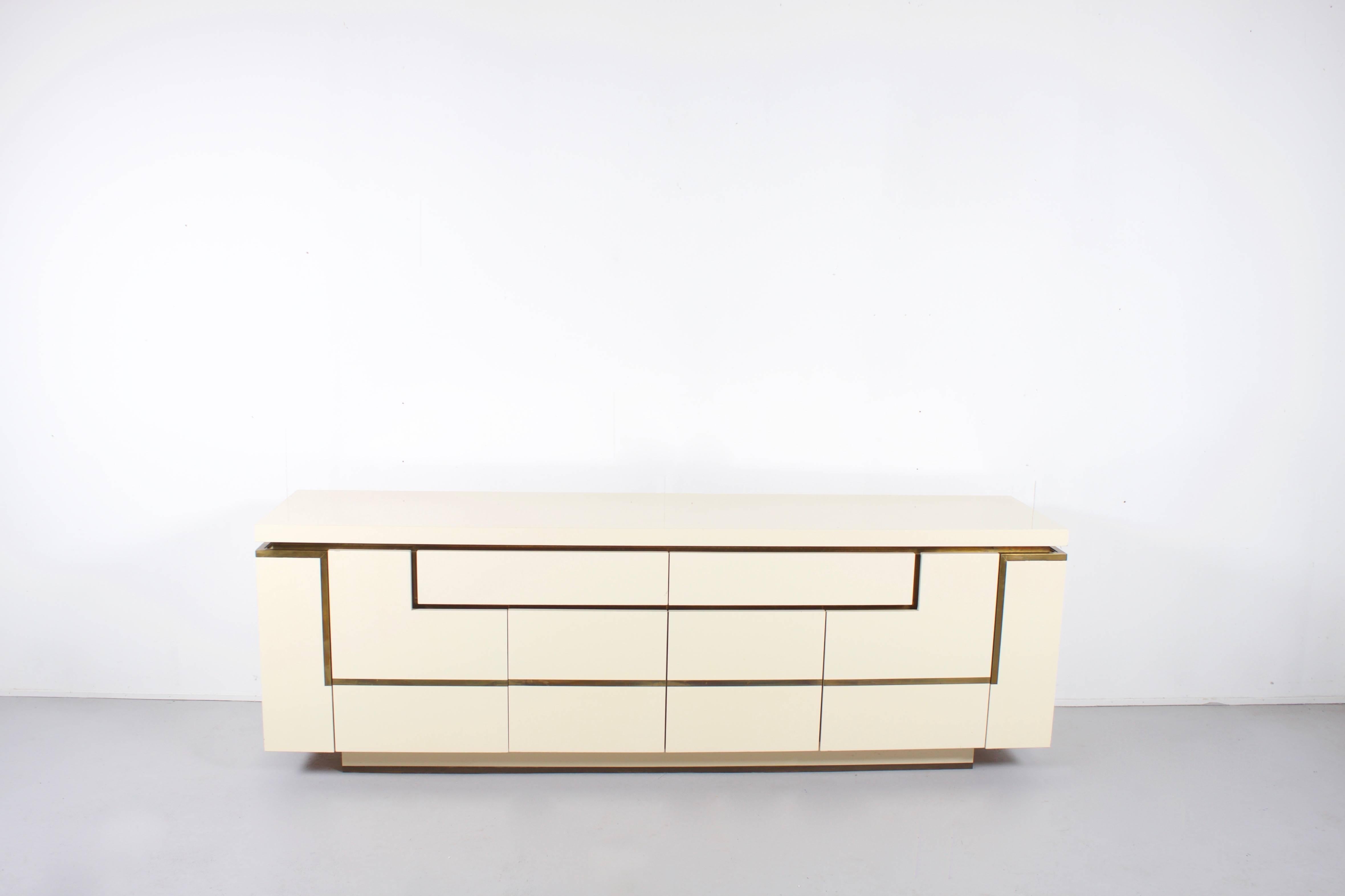 Impressive sideboard by the French designer Jean Claude Mahey in very good condition.

This sideboard is carried out in a beautiful high gloss off-white lacquer and has solid brass trimmed edges.

It has two main compartments with one shelf each,