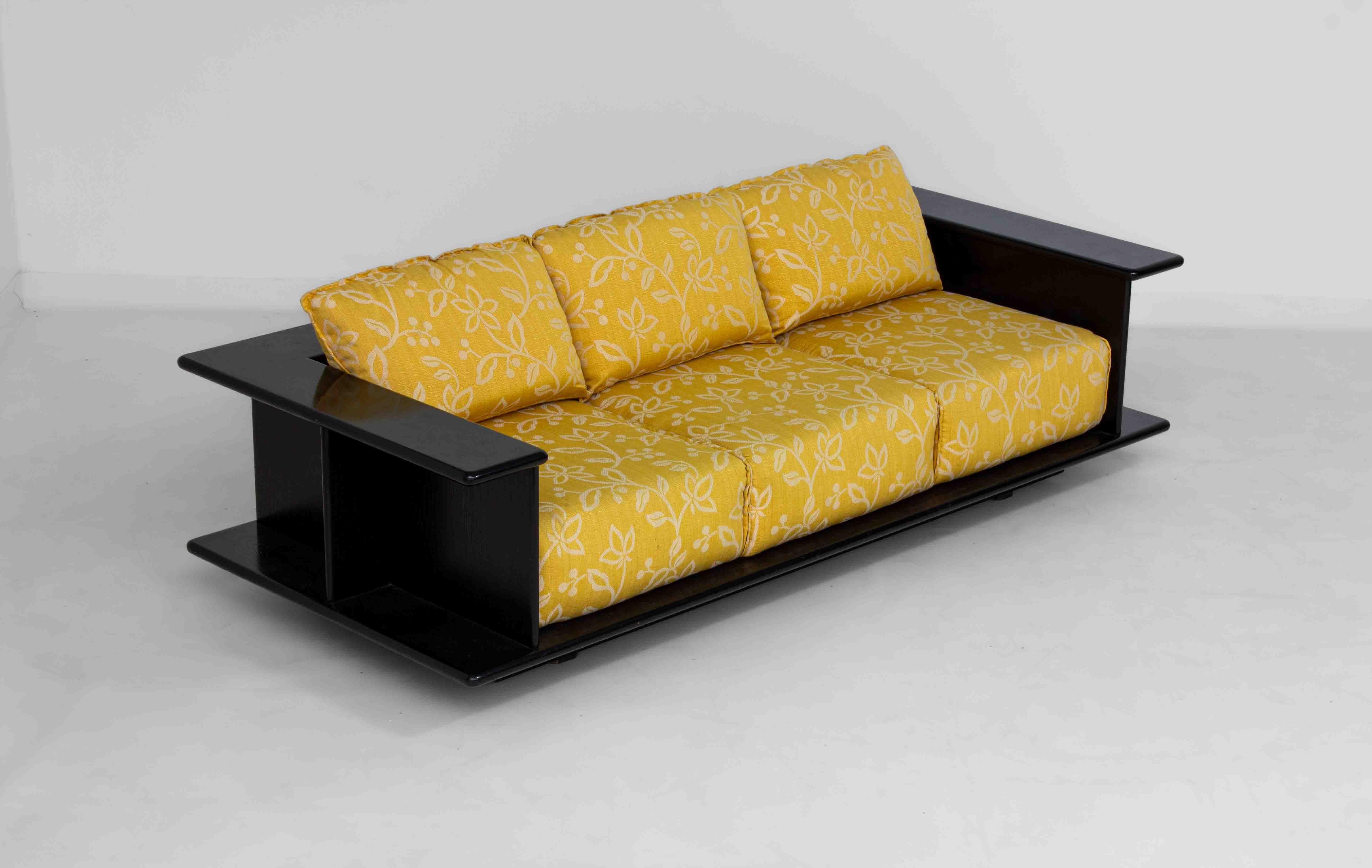 Skulpturales italienisches Dreisitzer-Sofa aus den 1970er Jahren, das Carlo Bartoli zugeschrieben wird, mit einem Rahmen aus schwarz lackiertem Holz, der um das gesamte Sofa herumgeht. Die breiten Armlehnen lassen sich nach außen ausfahren und