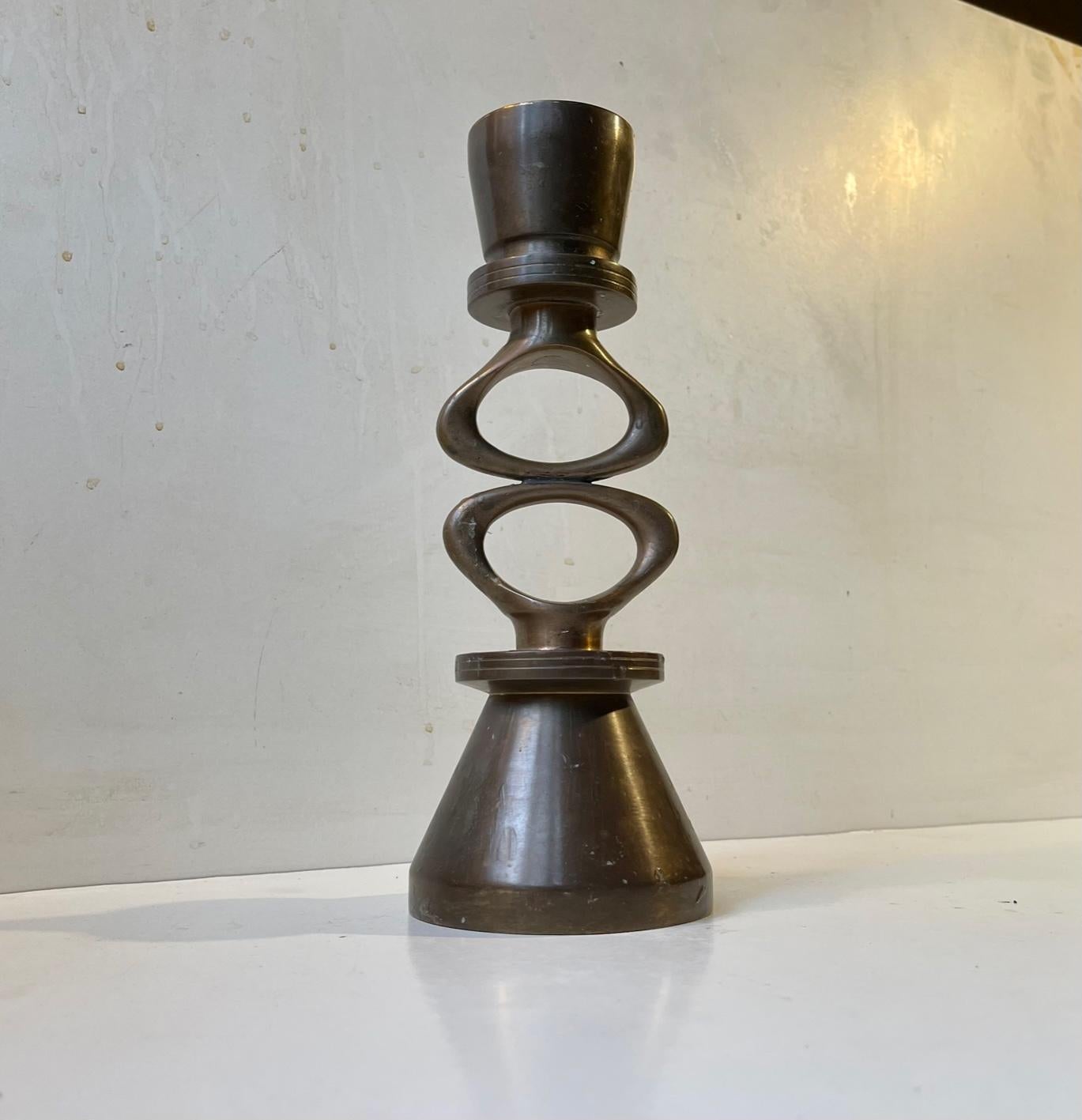 A well-made heavy stock candleholder for regular sized candles, block or ball candles. Its fashioned from solid bronze that has patinated during the last 50 years. It doubles as a sculpture with its abstract symbolic connecting center-parts. It was