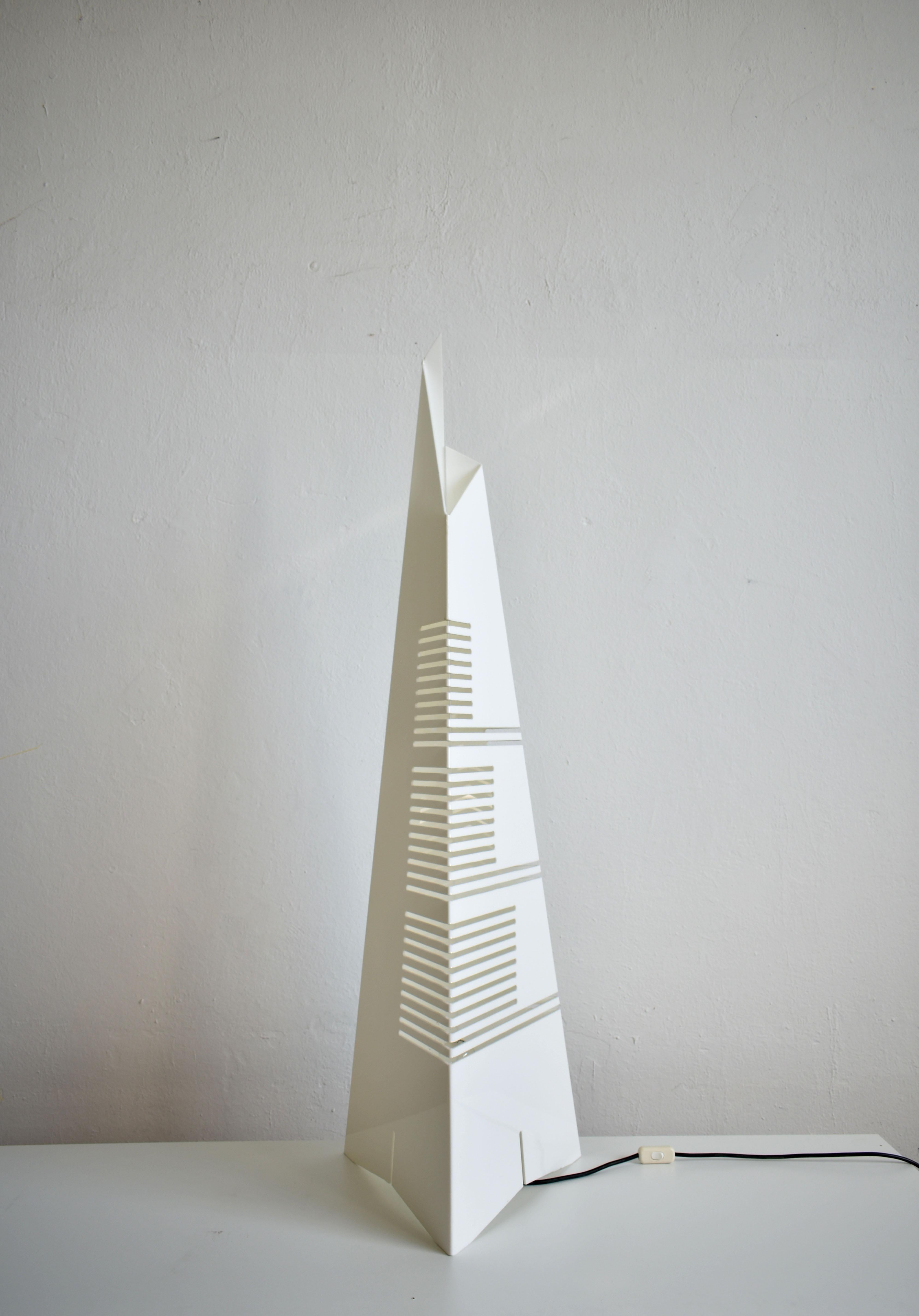 A rare architectural floor lamp 'Personaggi' made of white blended plexiglass sheet with geometrical cuts that form a pyramidal skyscraper

Designed in 1971 by Carmellini and Tronconi for Tronconi

The lamp has European plug, an E27 lamp socket
