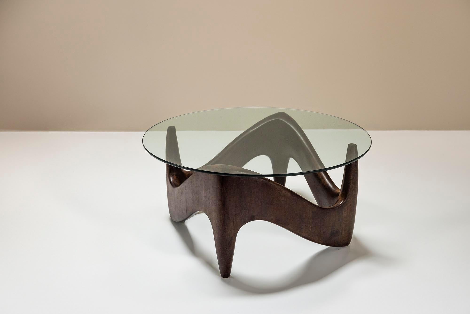 Sculptural and organic-shaped coffee table with a wooden base and glass top. The playful design is a combination of a square-shaped base, although when you look differently at it, it can also look as a triangle, the organic flow of the wood and the