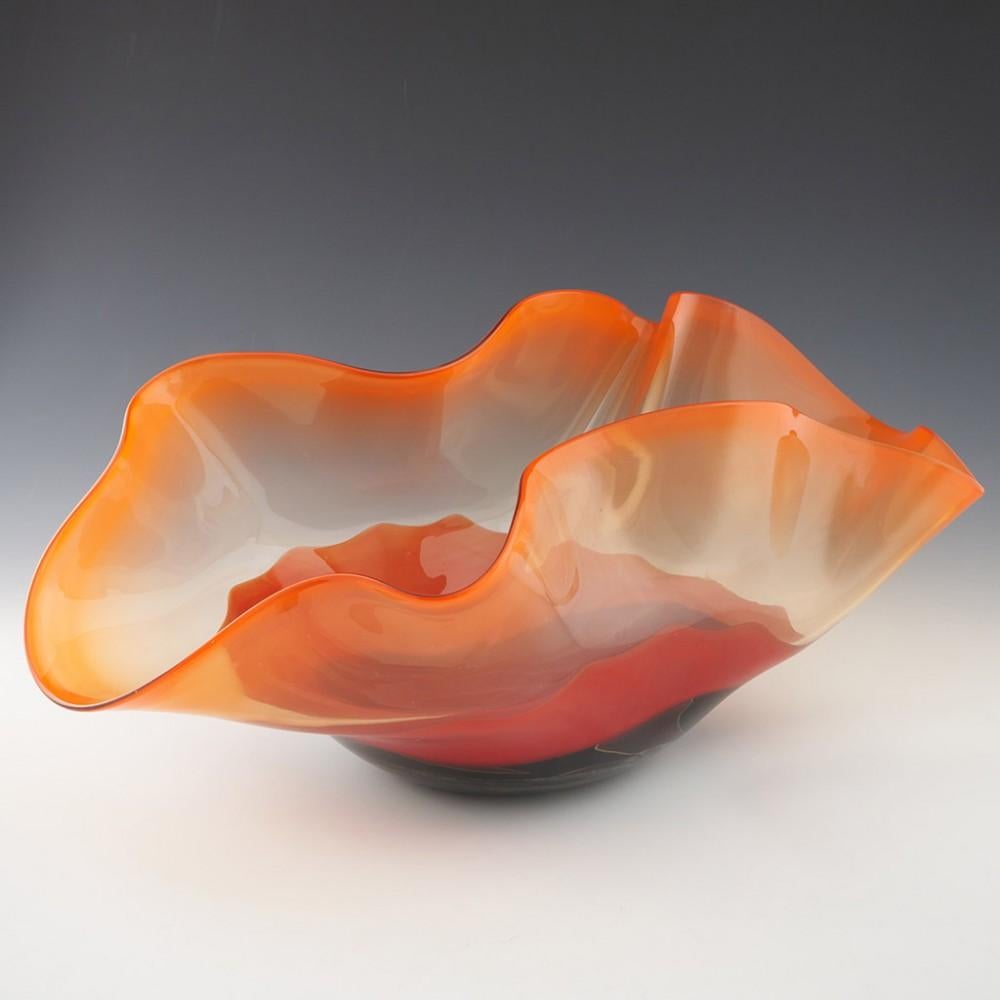 Heading : Large Peter Layton glass bowl
Date : c2000
Origin : London, England
Bowl Features : A sculptural piece. Crimped wave like rim in sunset orange graduating to clear and crimson with a black and marbled base.
Marks : Signed Anthony Stern to