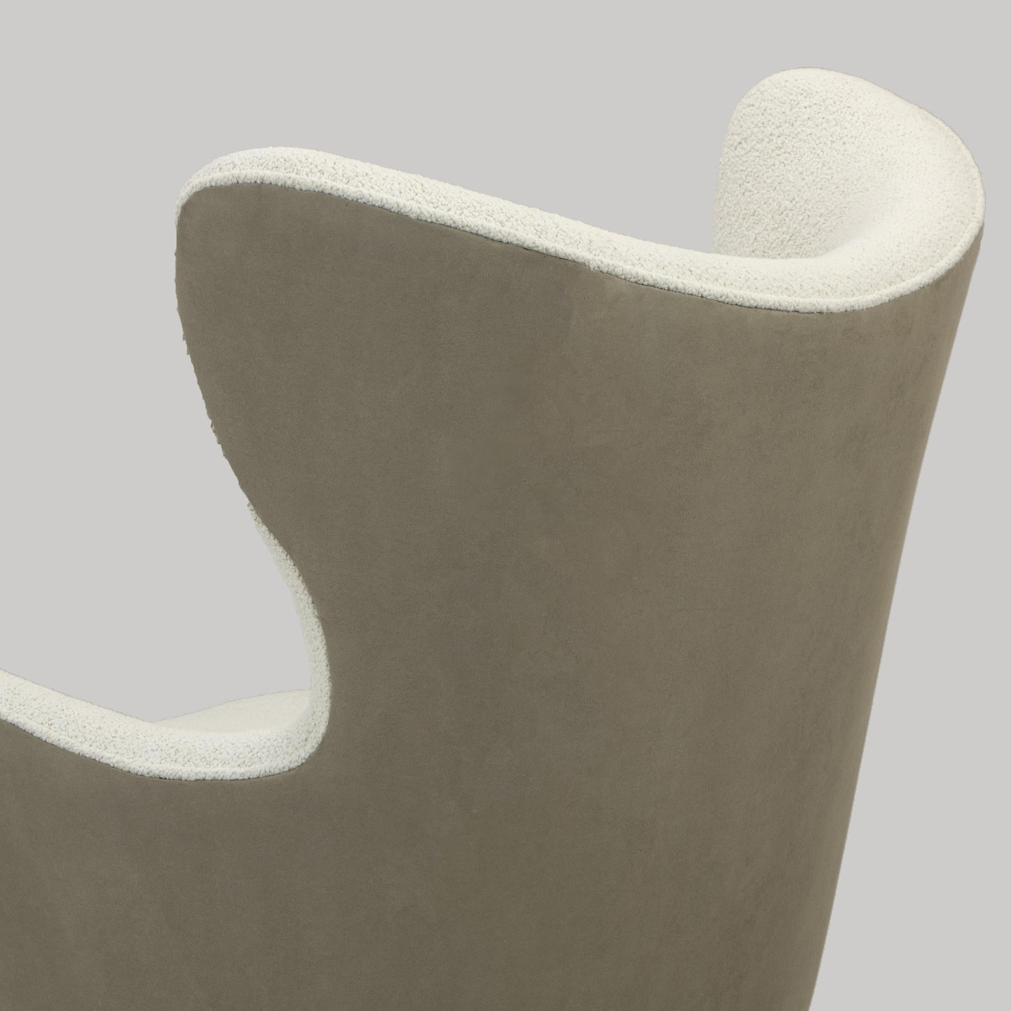 Ce fauteuil contemporain est une étude de l'élégance minimaliste et du luxe subtil. Elle est dotée d'une assise et d'un dossier rembourrés et moelleux, magnifiquement définis par un simple passepoil, qui souligne la silhouette épurée de la chaise.