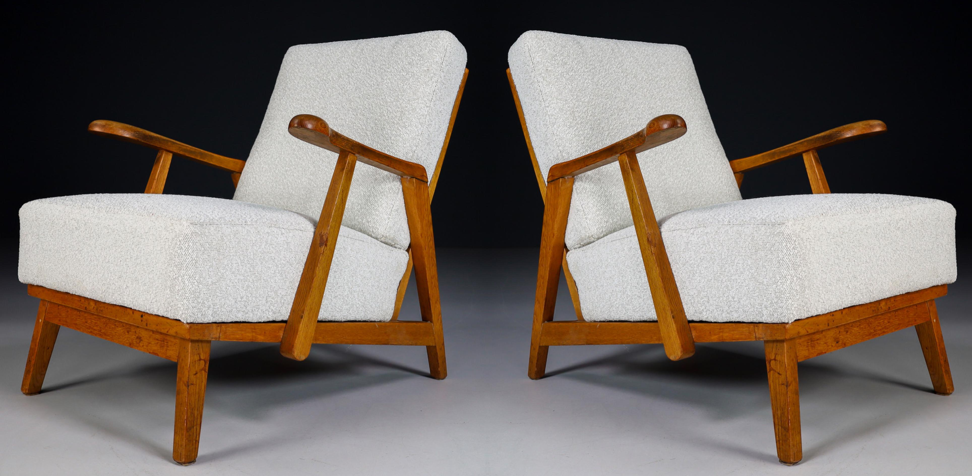 Pair of two original midcentury sculptural armchairs or lounge chairs manufactured and designed in France 1940s. Made of solid oak and professionally reupholstered in new bouclé fabric. These armchairs would make an eye-catching addition to any