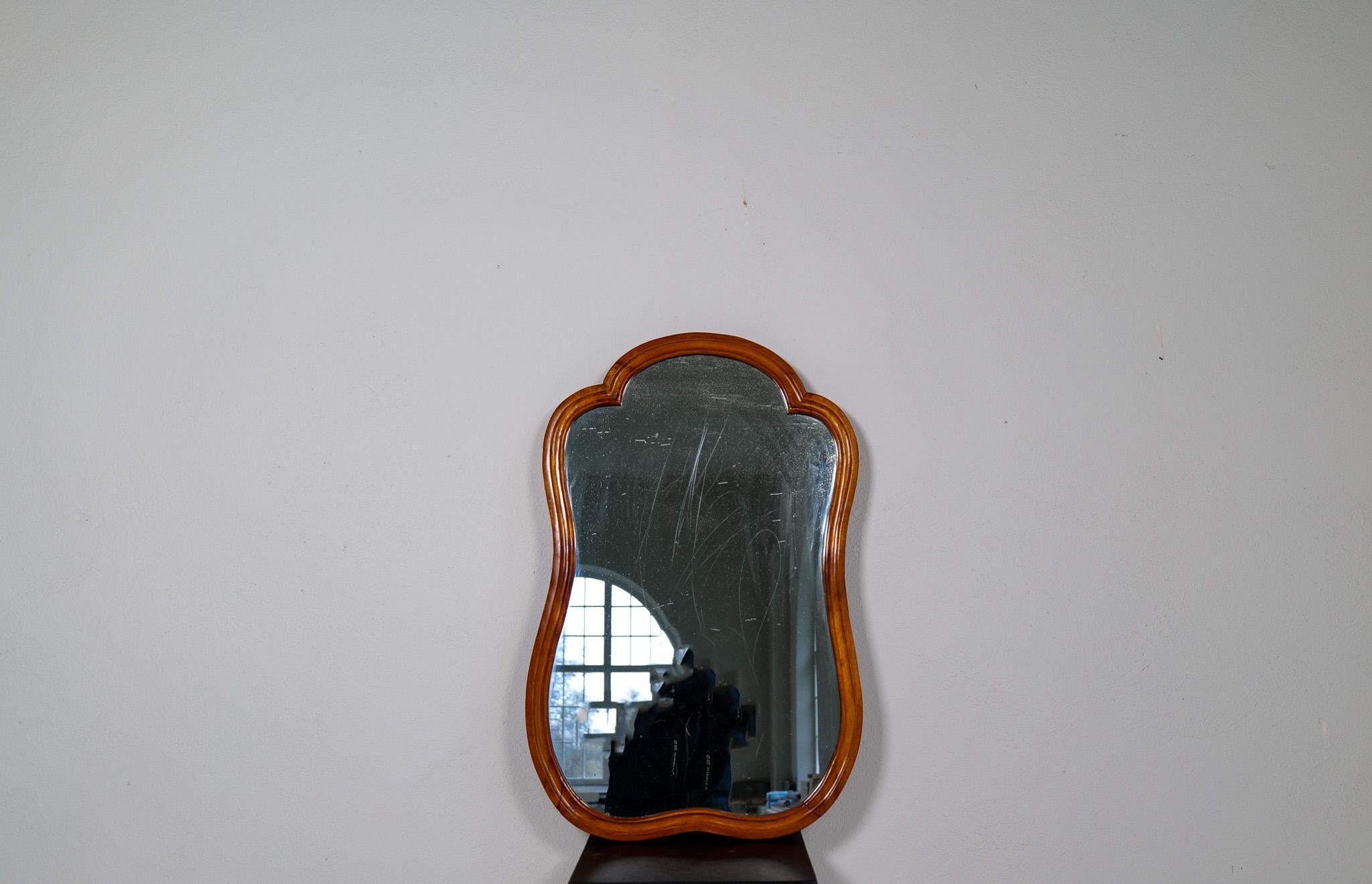 Sculptural wall mirror in walnut, produced in Sweden during the 1920s.
The mirror is made in walnut. The mirror itself is made with curvy sculptural lines.

Good vintage condition, small scratches, and the glass somewhat distressed. Small holes