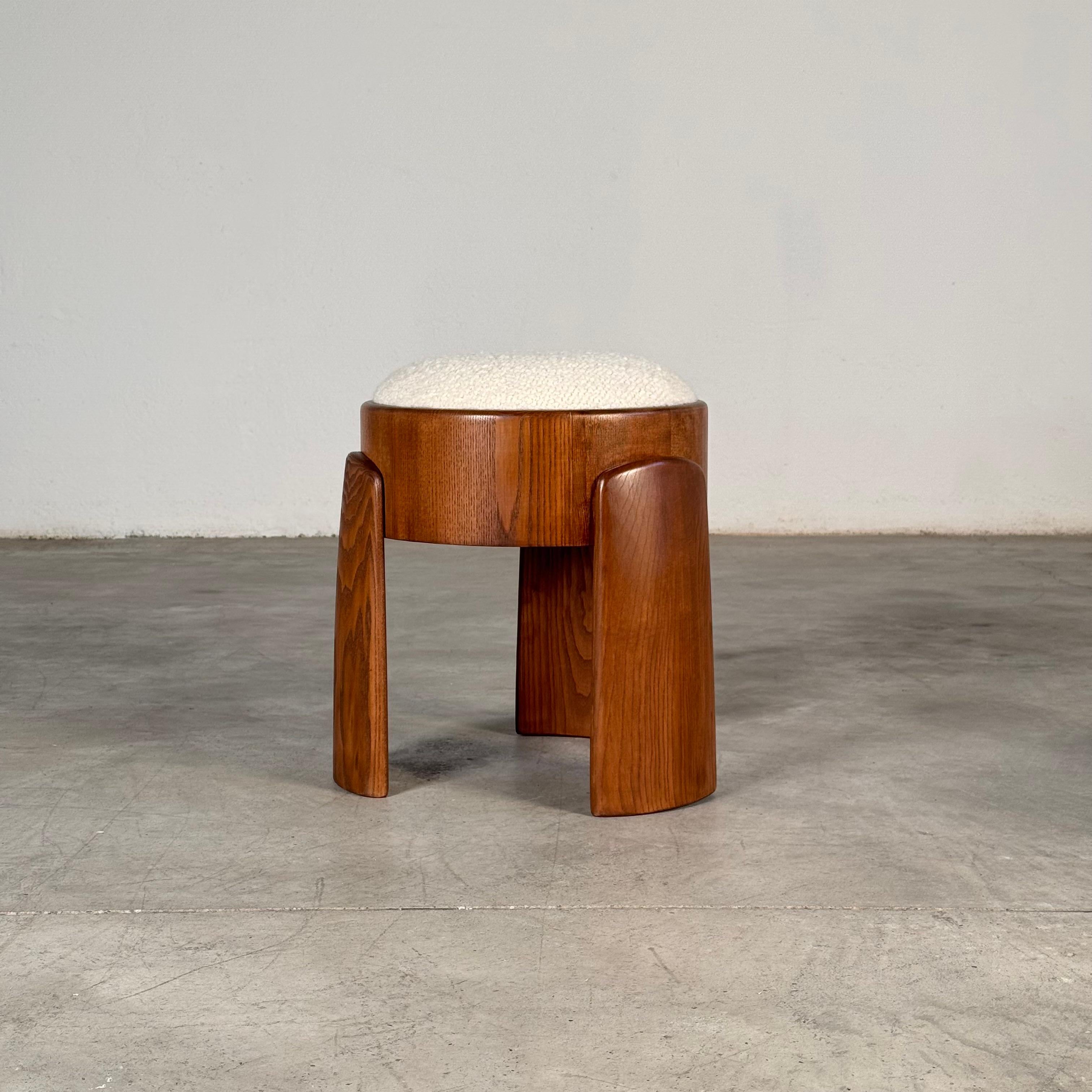 Oda escultórica a la textura y la proporción, este taburete artesanal encarna la fusión perfecta de rigor arquitectónico y sensualidad táctil. Su base de madera maciza de fresno, audaz, geométrica y profundamente táctil, ancla el diseño con una